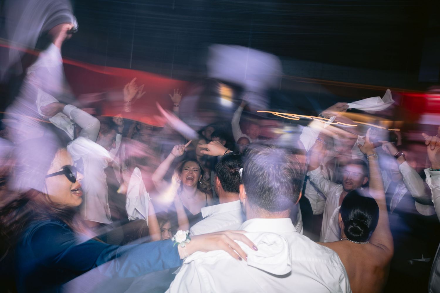 Blurred motion shot of people dancing at a nightclub with red lighting creates an energetic atmosphere.