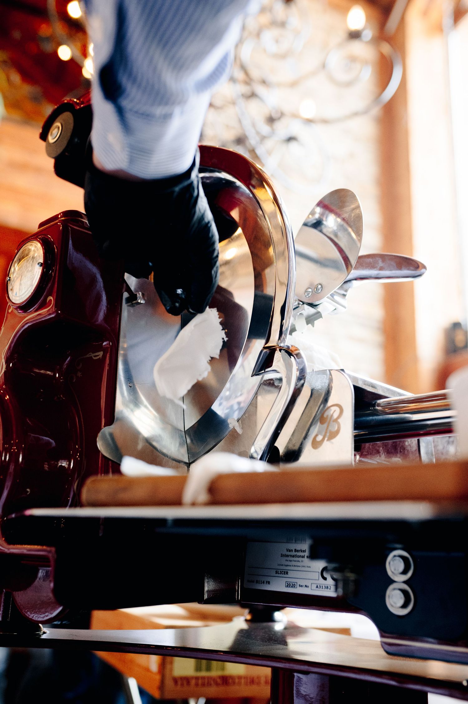 Close-up view of hands grinding fresh coffee beans in a manual burr grinder with warm lighting in background.