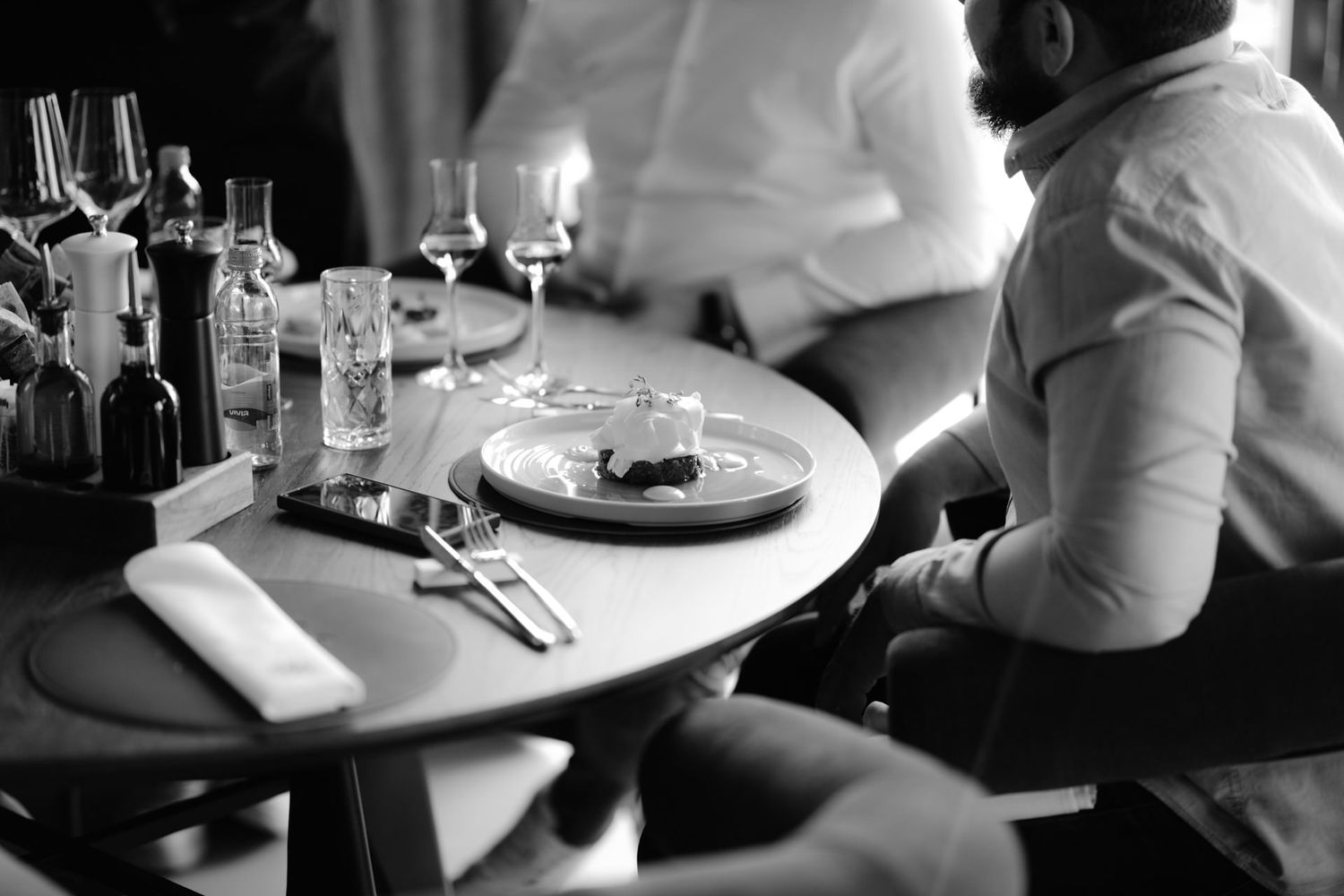 Black and white photograph of diners at restaurant tables.