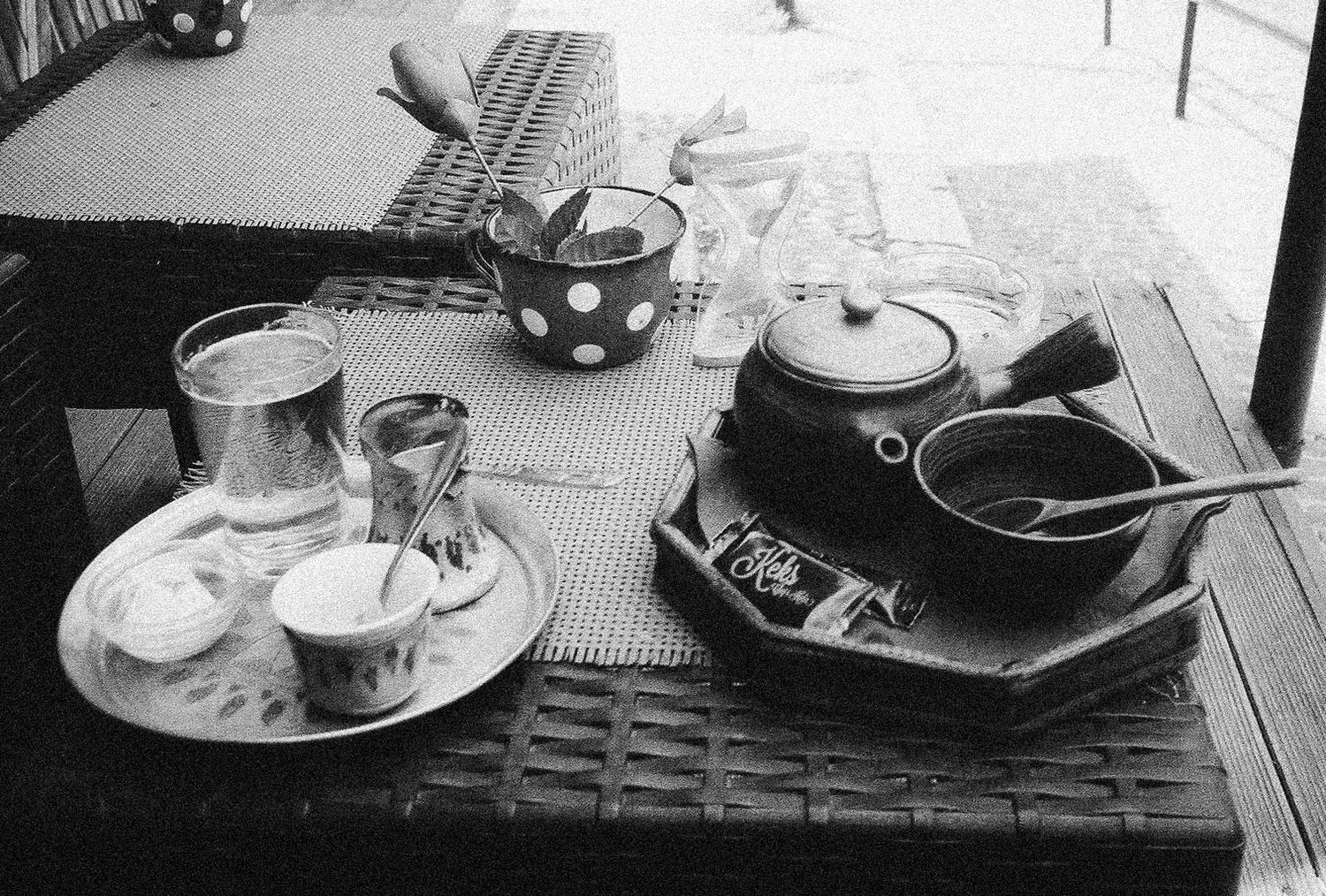 Black and white photo series showing coffee cups, pastries and drinks arranged on various cafe tables and surfaces.
