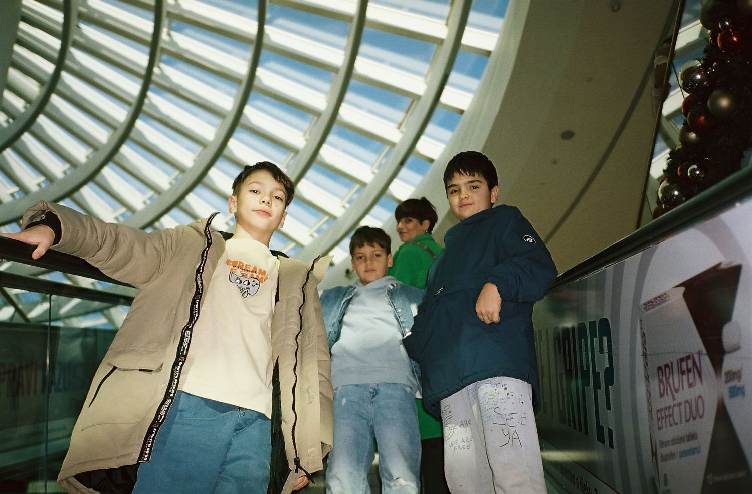 People walking through a modern building interior with curved glass ceiling and natural lighting.