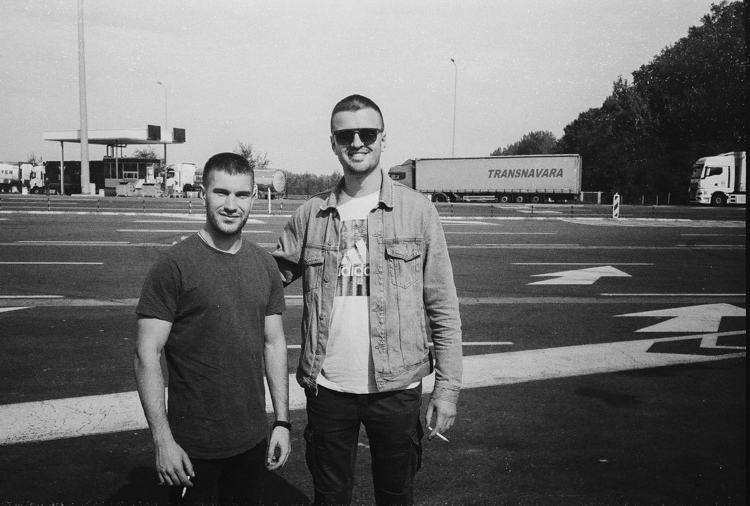 Two people stand together outdoors in a black and white vintage photograph.