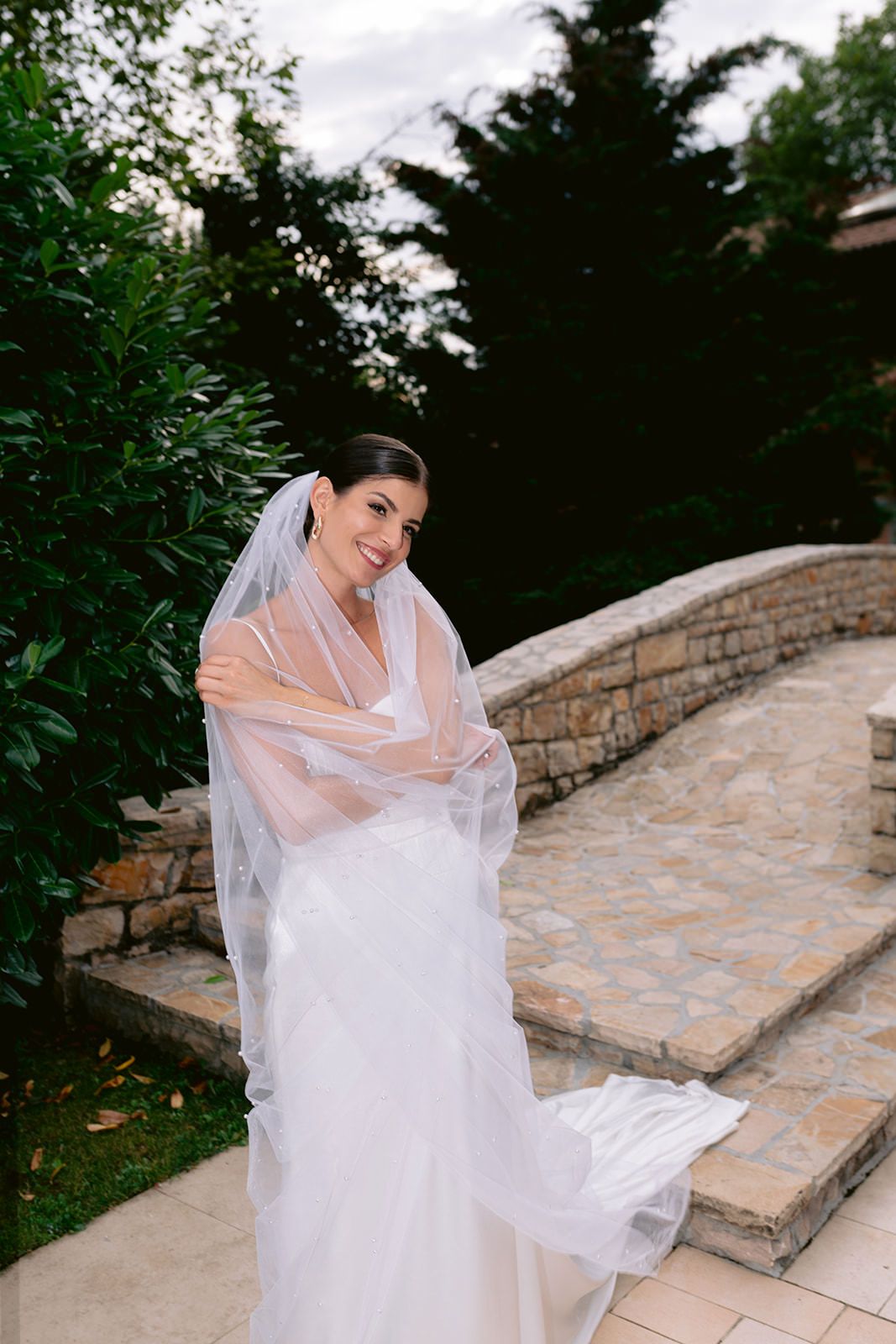 Joyful bridal moment captured on stone steps surrounded by greenery.