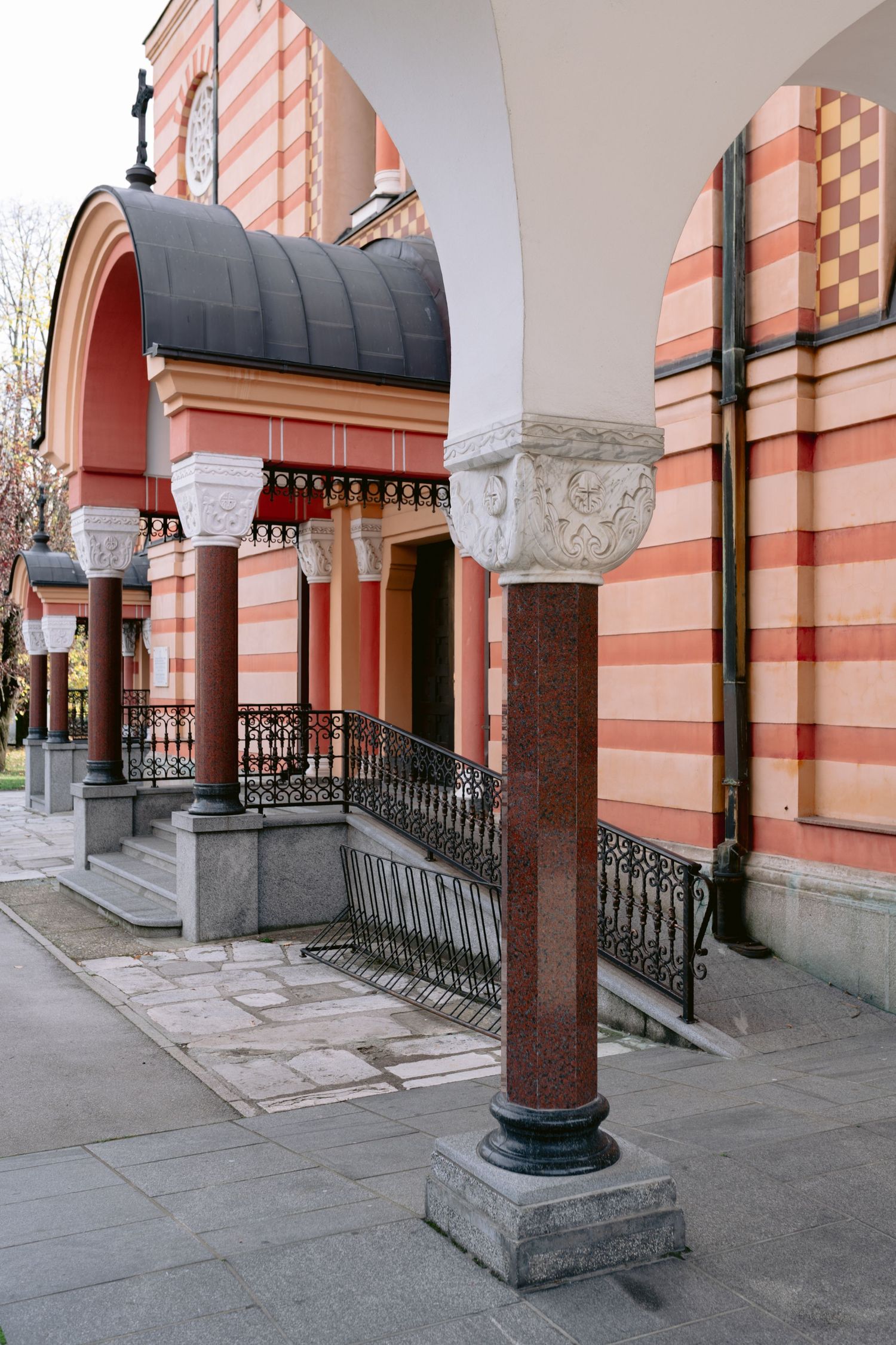 Ornate pink and white striped archways with decorative columns and wrought iron railings at a historic building entrance.