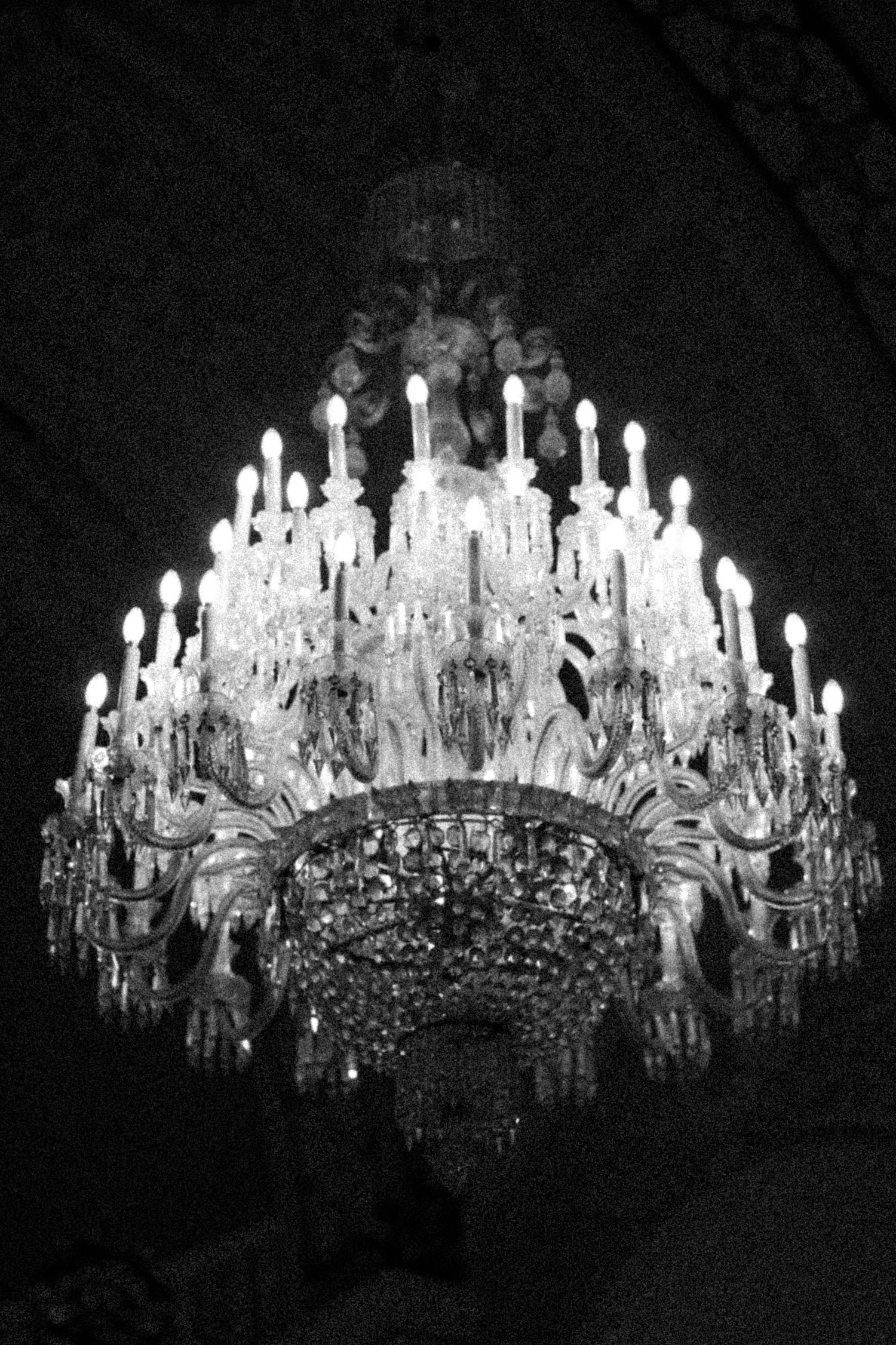 A sequence of black and white photographs showing an ornate crystal chandelier illuminated against a dark background.