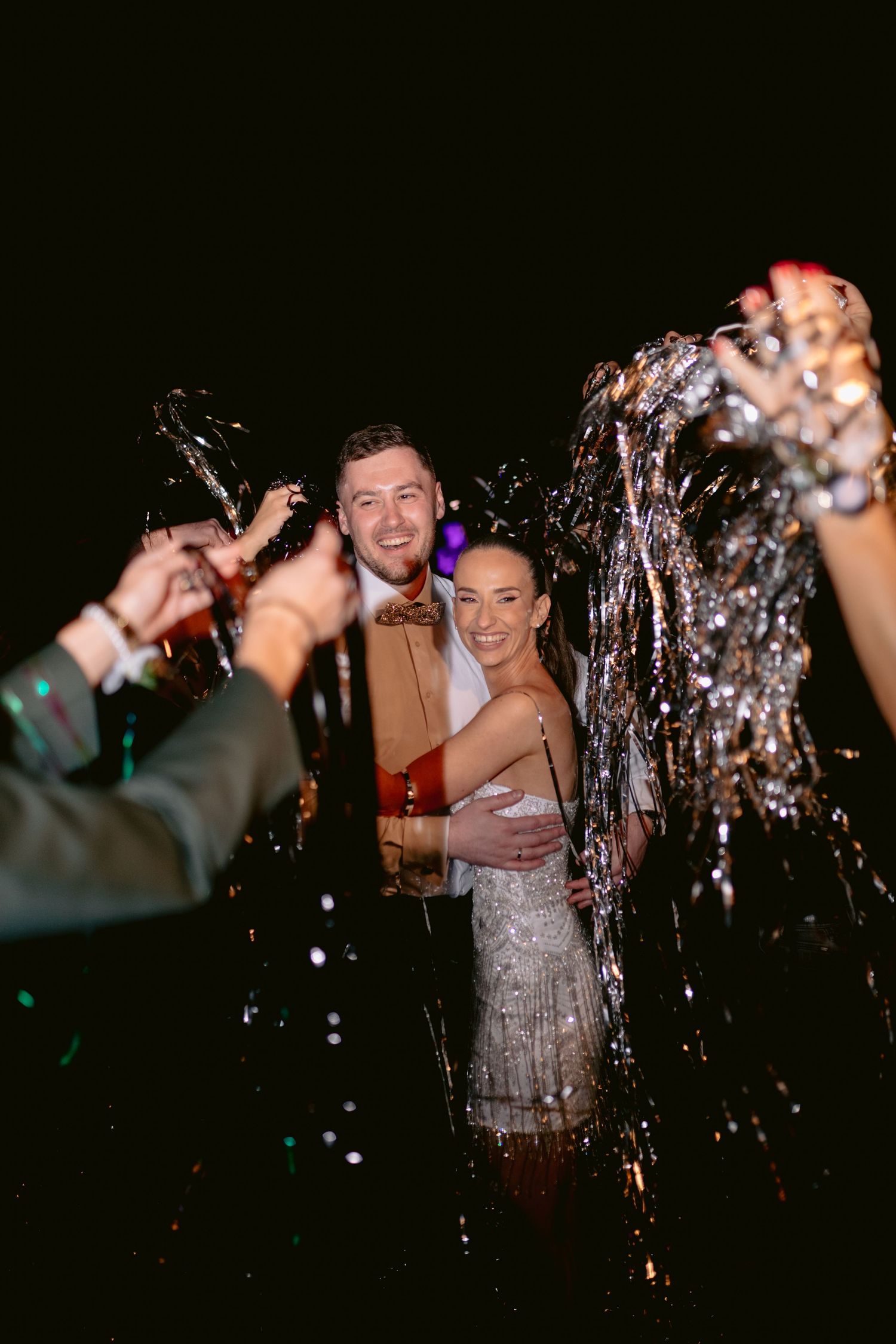 Celebratory moment at a party with champagne spraying and people in festive attire enjoying the nighttime celebration.