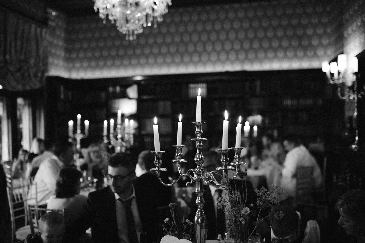 Atmospheric reception scene with glowing candelabras and chandelier in dark setting.