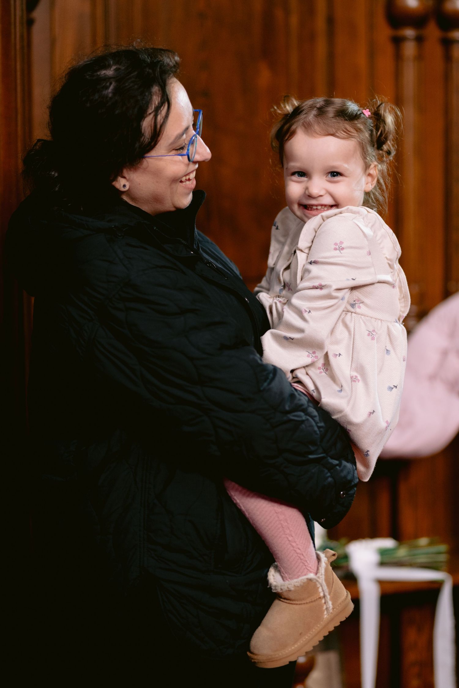 A heartwarming moment of laughter and joy between two people sharing an embrace in a warm wooden interior setting.