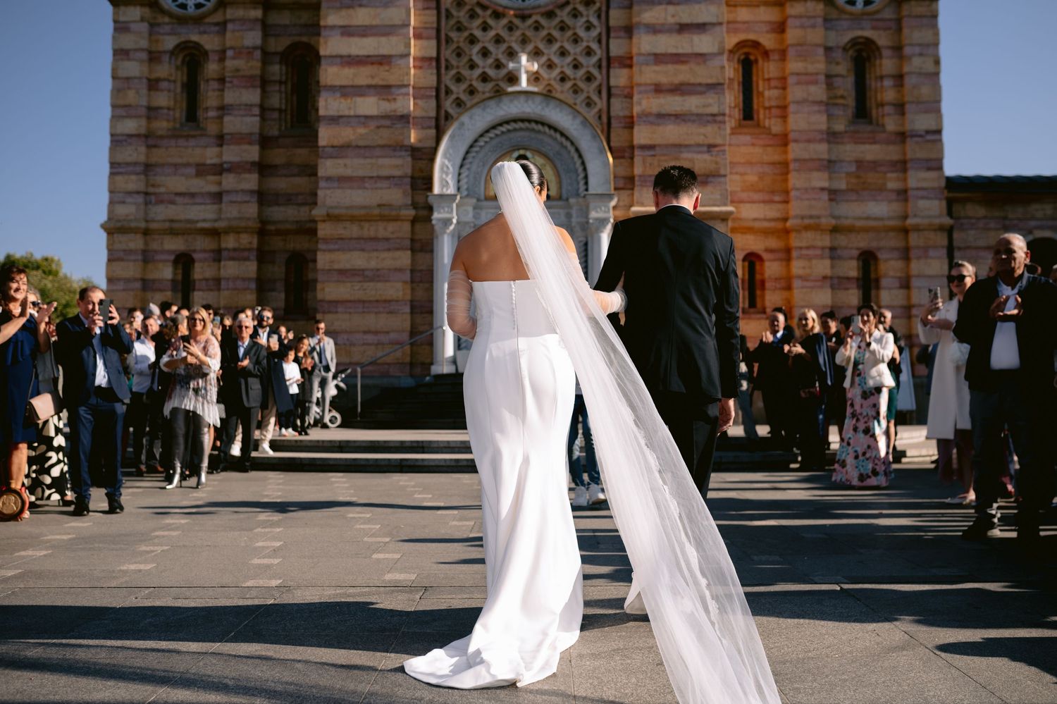 Wedding ceremony outside historic brick church building with gathered guests.
