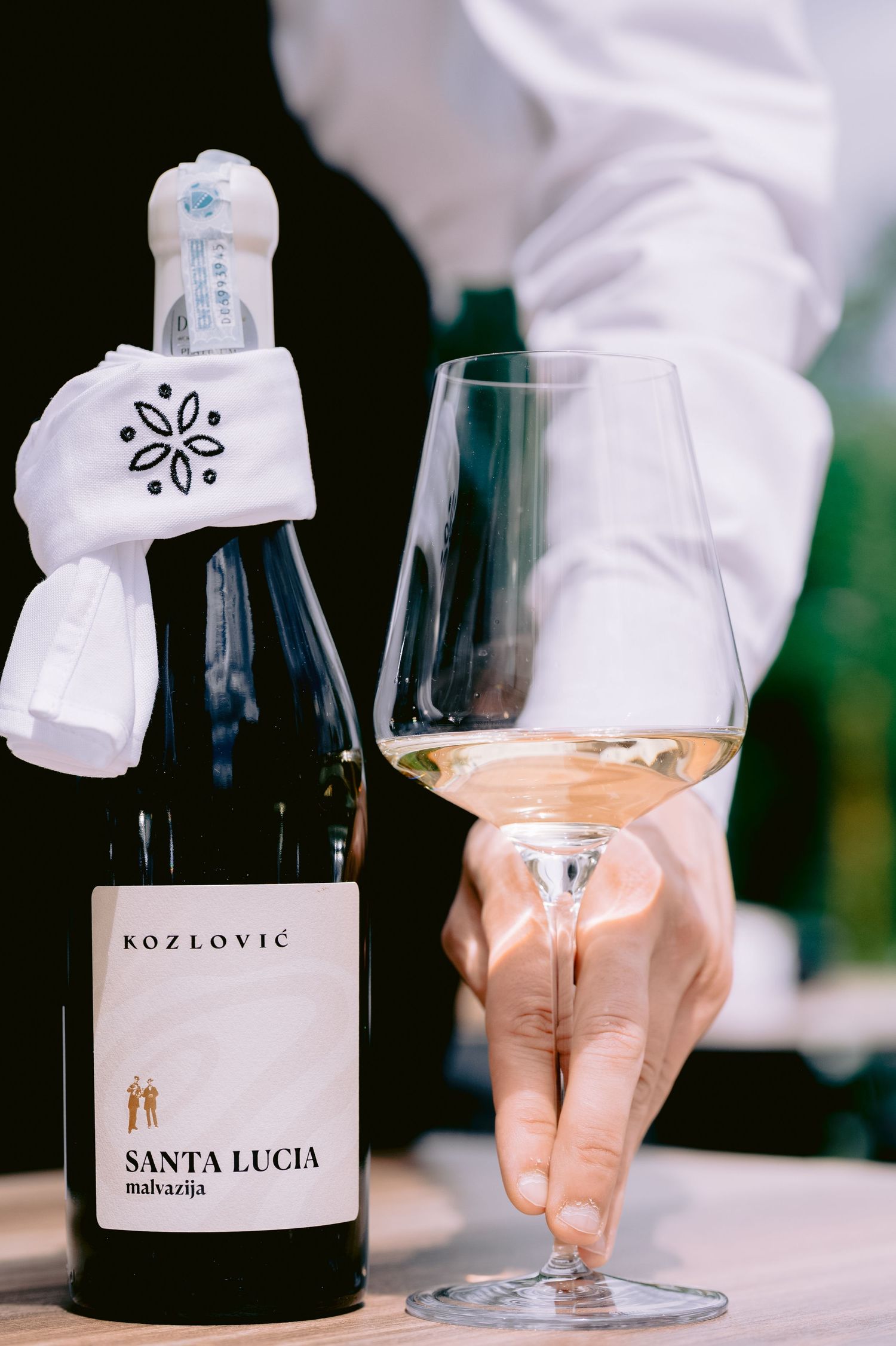 Santa Lucia Kozlovic wine bottle being served with white napkin.
