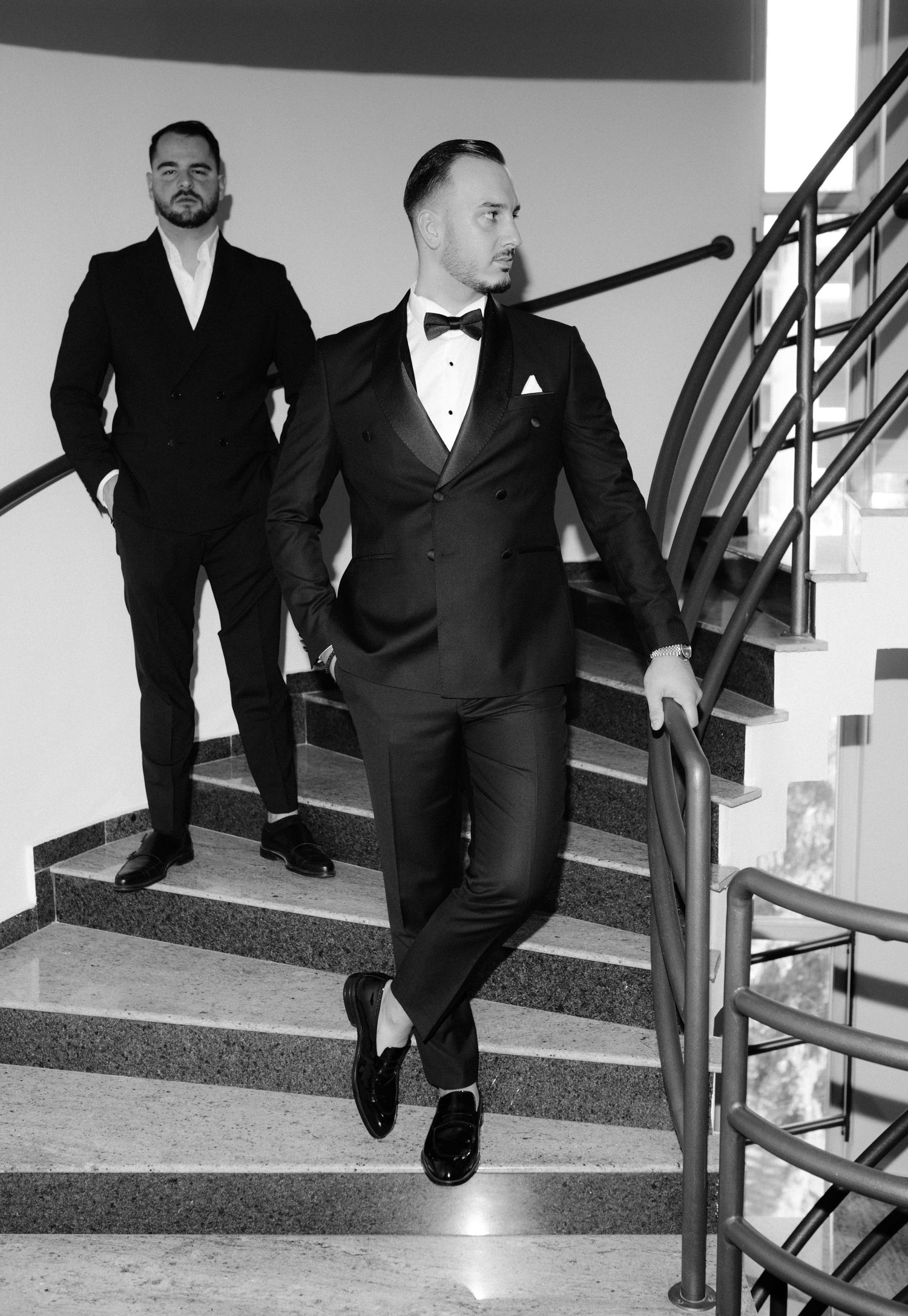 A black and white photo series showing five different poses of a person sitting on stairs wearing a formal suit.