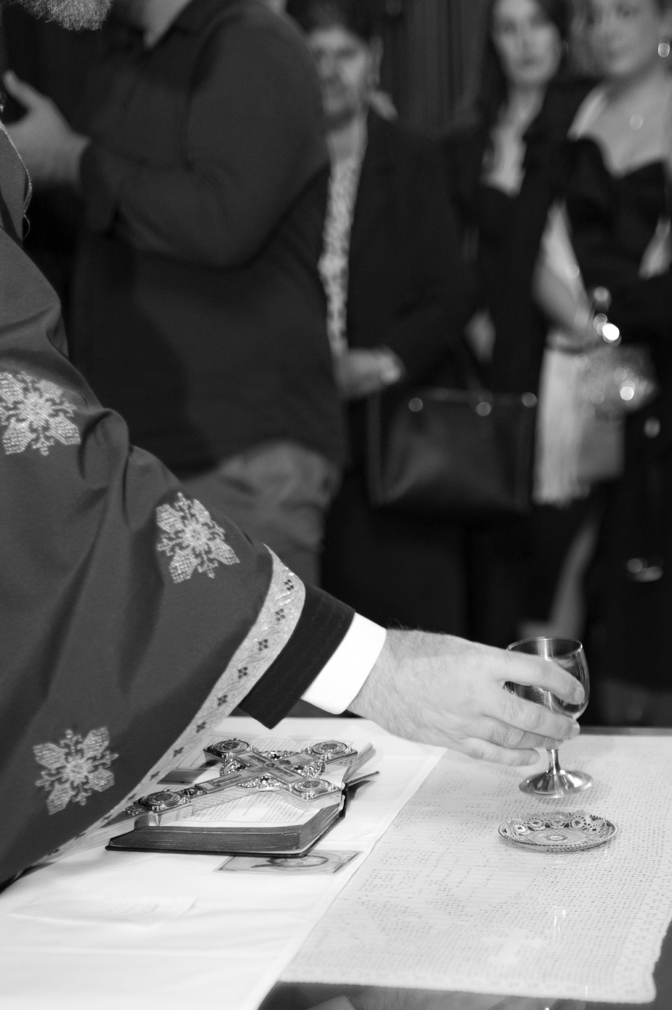 A black and white wedding photo showing hands signing documents at a formal ceremony.