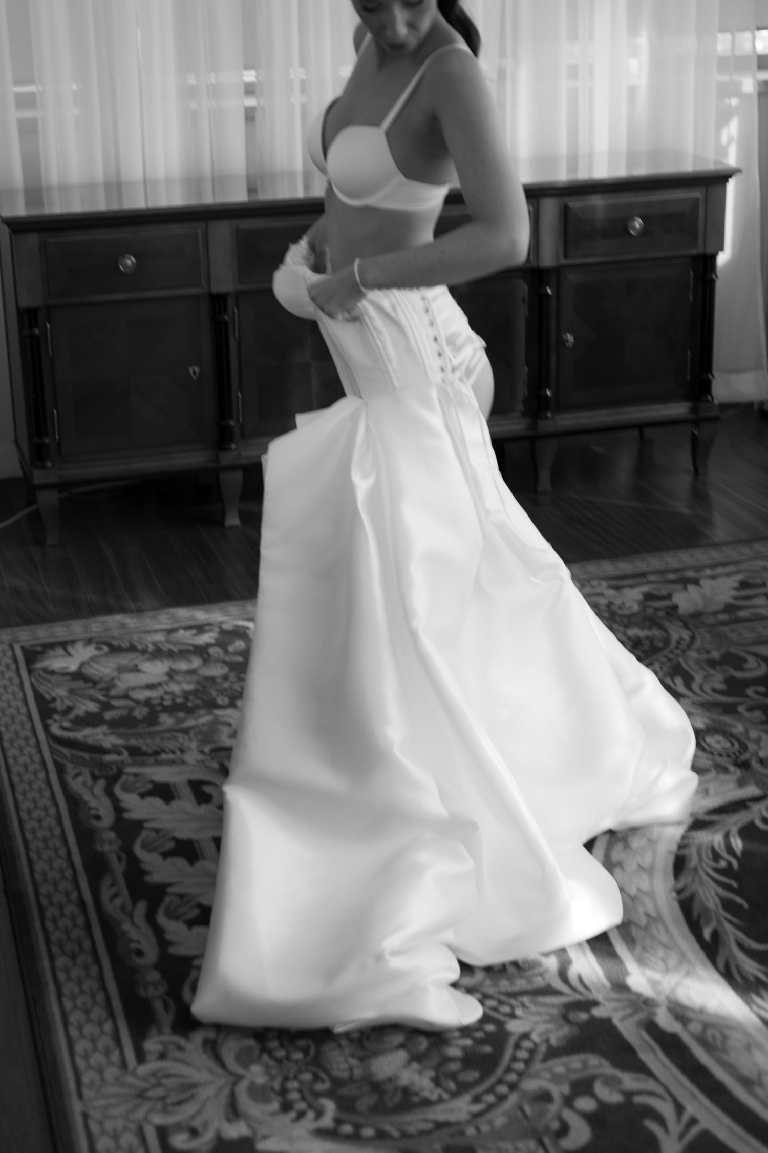 A sequence of black and white photos showing the flowing movement of a white wedding dress on a patterned carpet.