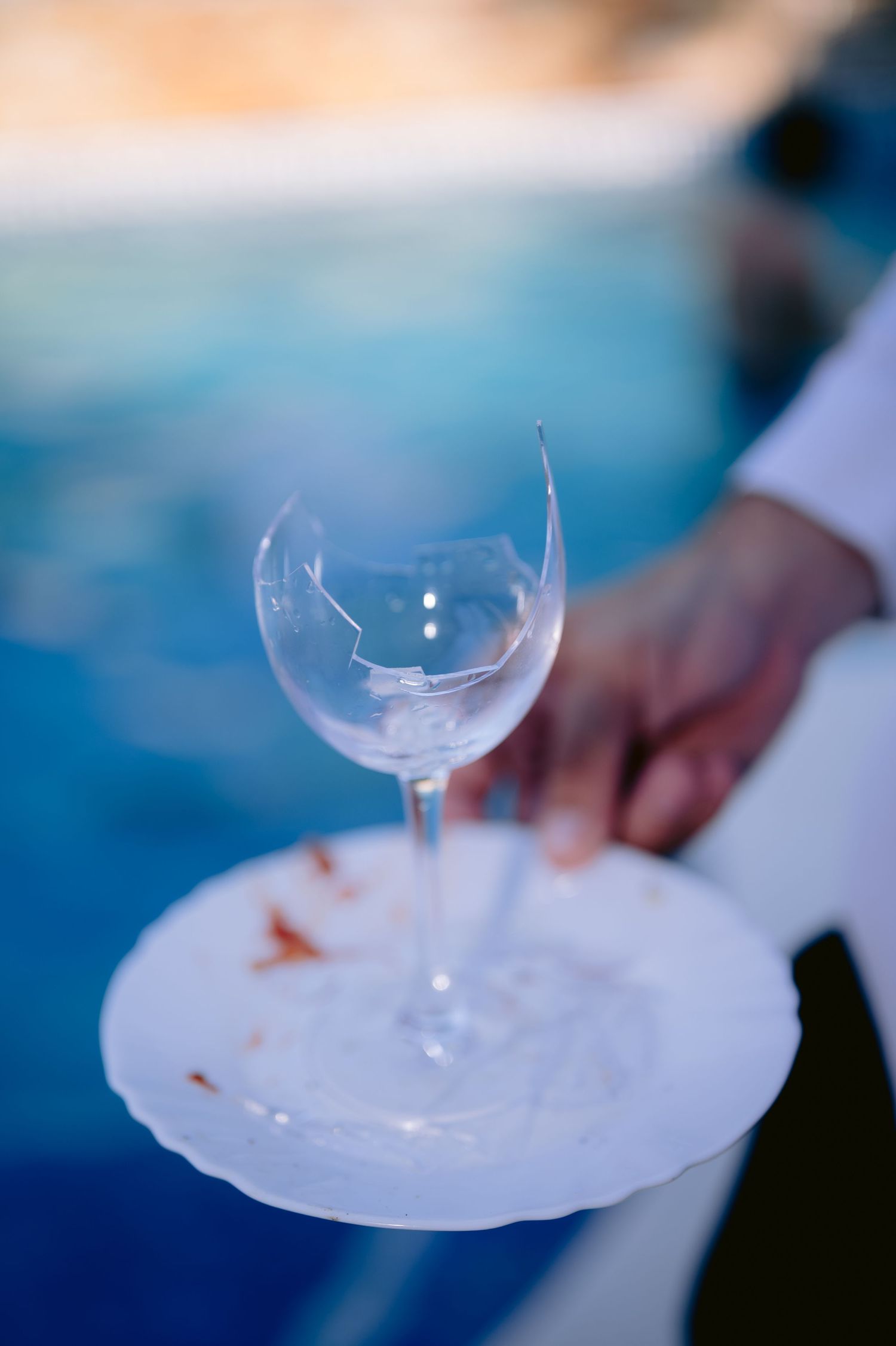 Razbijena čaša za vino na bijelom tanjiru pored bazena, pool party vjenčanje Villa Slatina Banja Luka