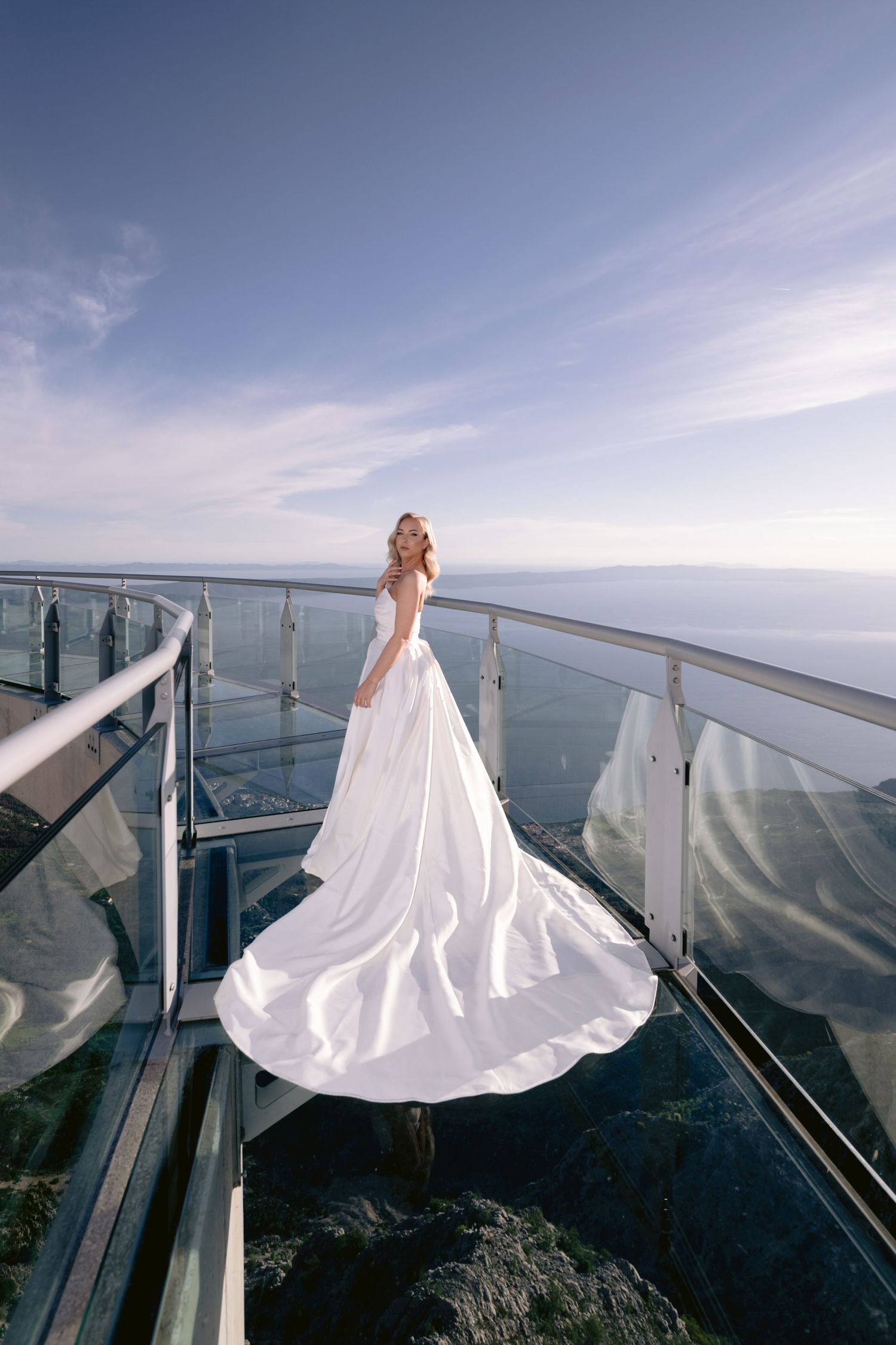 Elegantna bijela vjenčanica sa dugačkim šlepom fotografisana na vidikovcu Biokovo sa pogledom na Jadransko more.