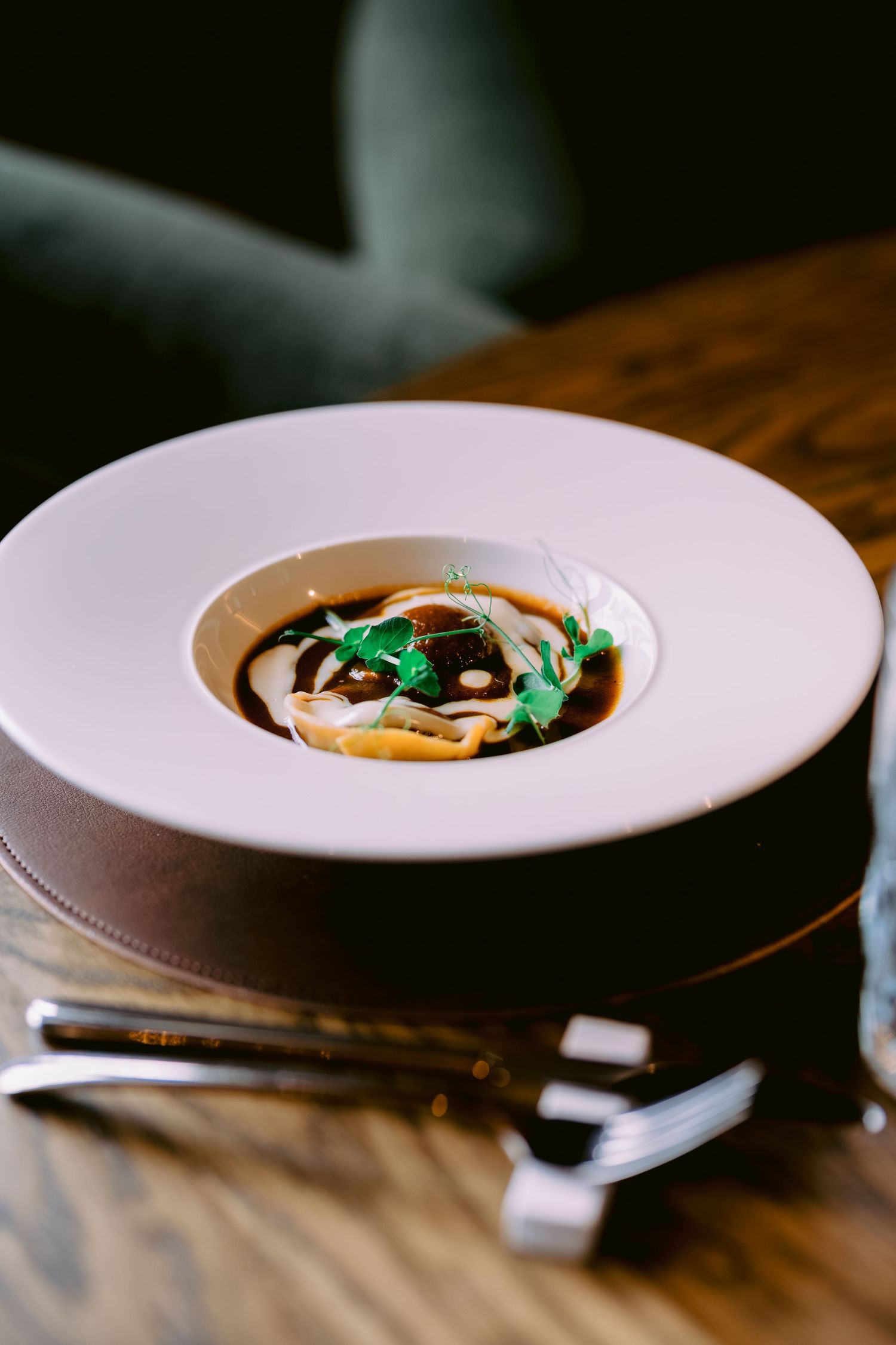 Creamy soup garnished with herbs and drizzle in white bowl.