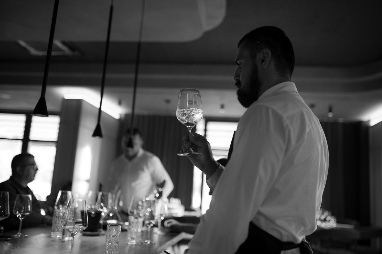 Professional kitchen interior with staff preparing dishes at service stations.