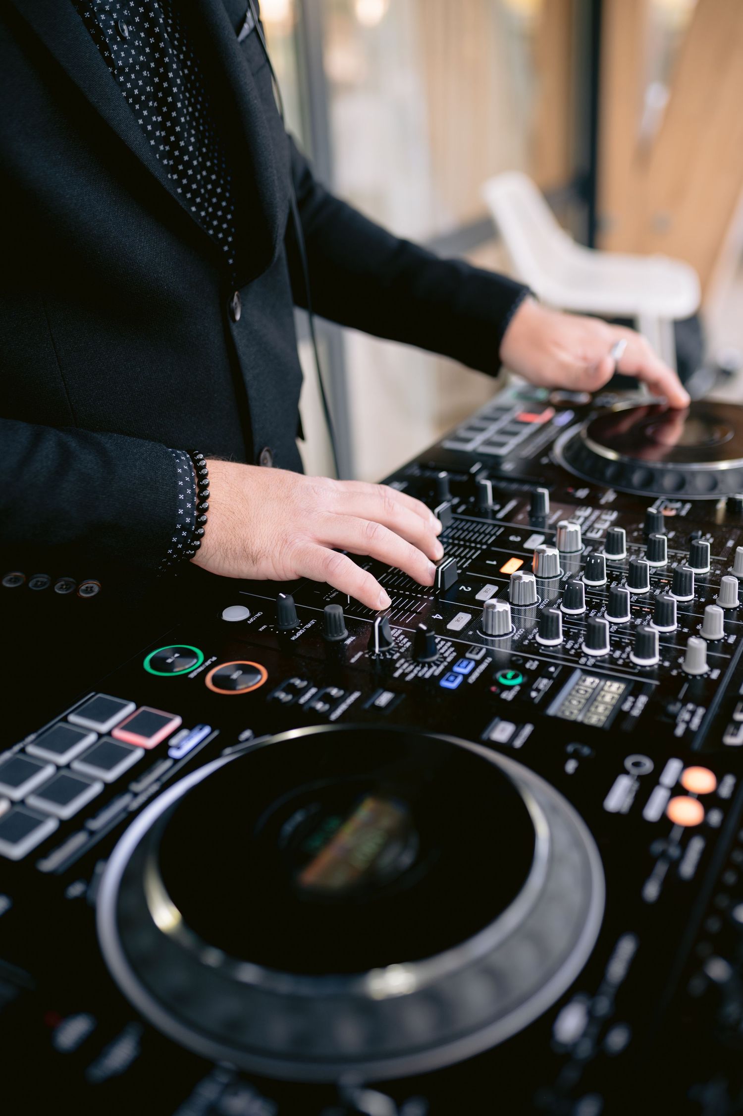 DJ hands working on professional mixing controller deck with knobs and buttons at music event.
