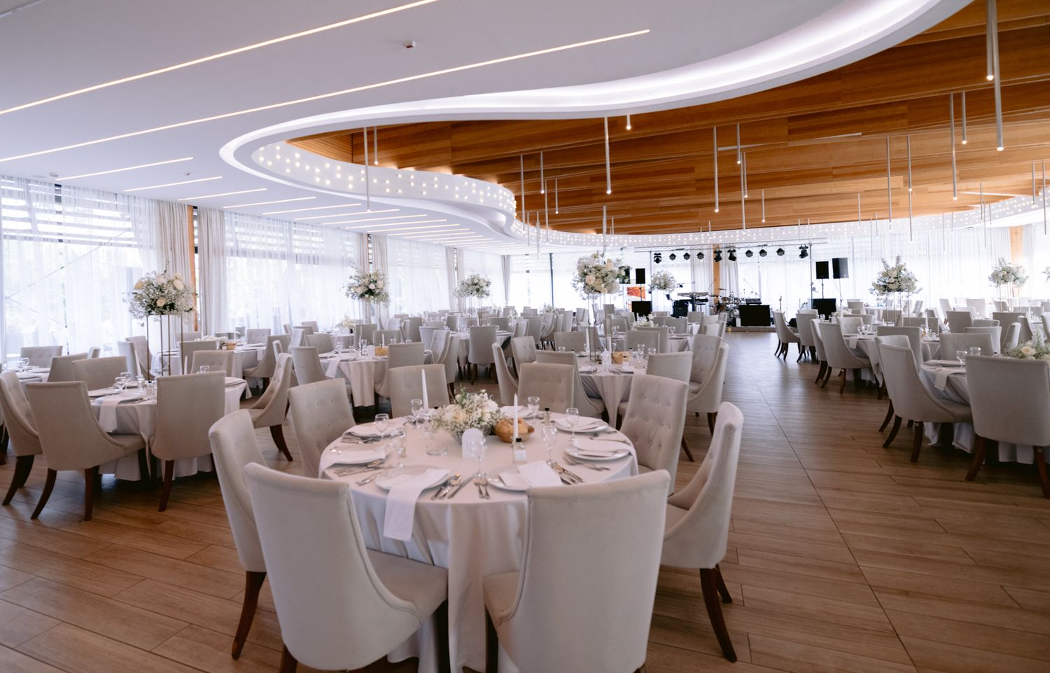 Modern wedding reception venue with white chairs and curved ceiling details.