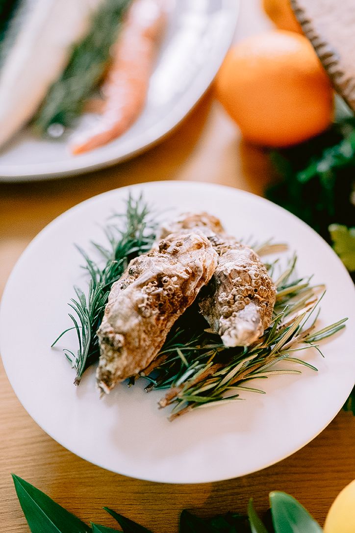 Oysters garnished with fresh rosemary sprigs on white plates.