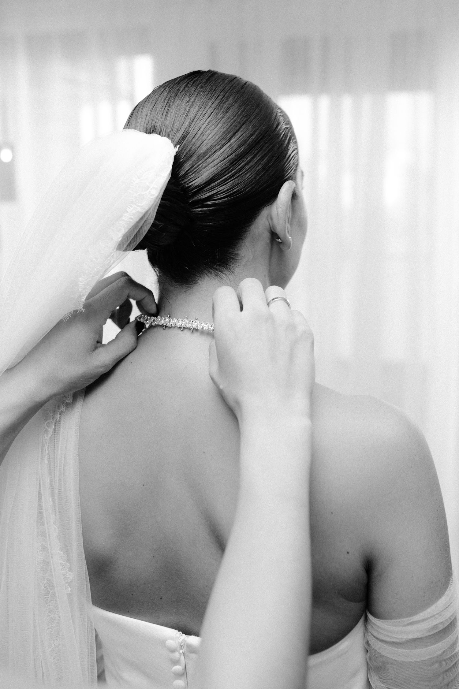 Black and white photo series showing close-up views of a bride's elegant updo hairstyle and veil from different angles.