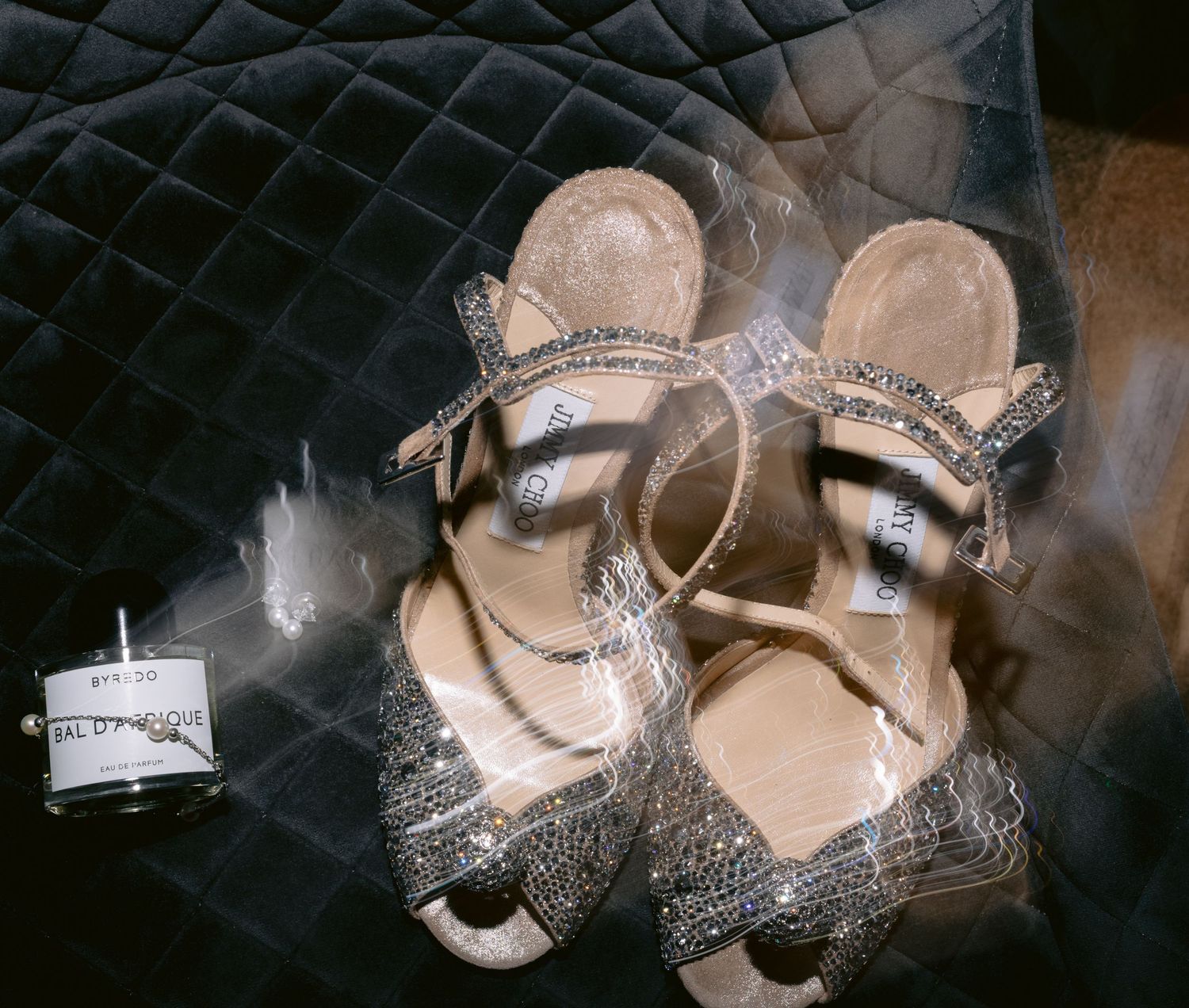 Crystal-embellished bridal shoes photographed on dark textured background.