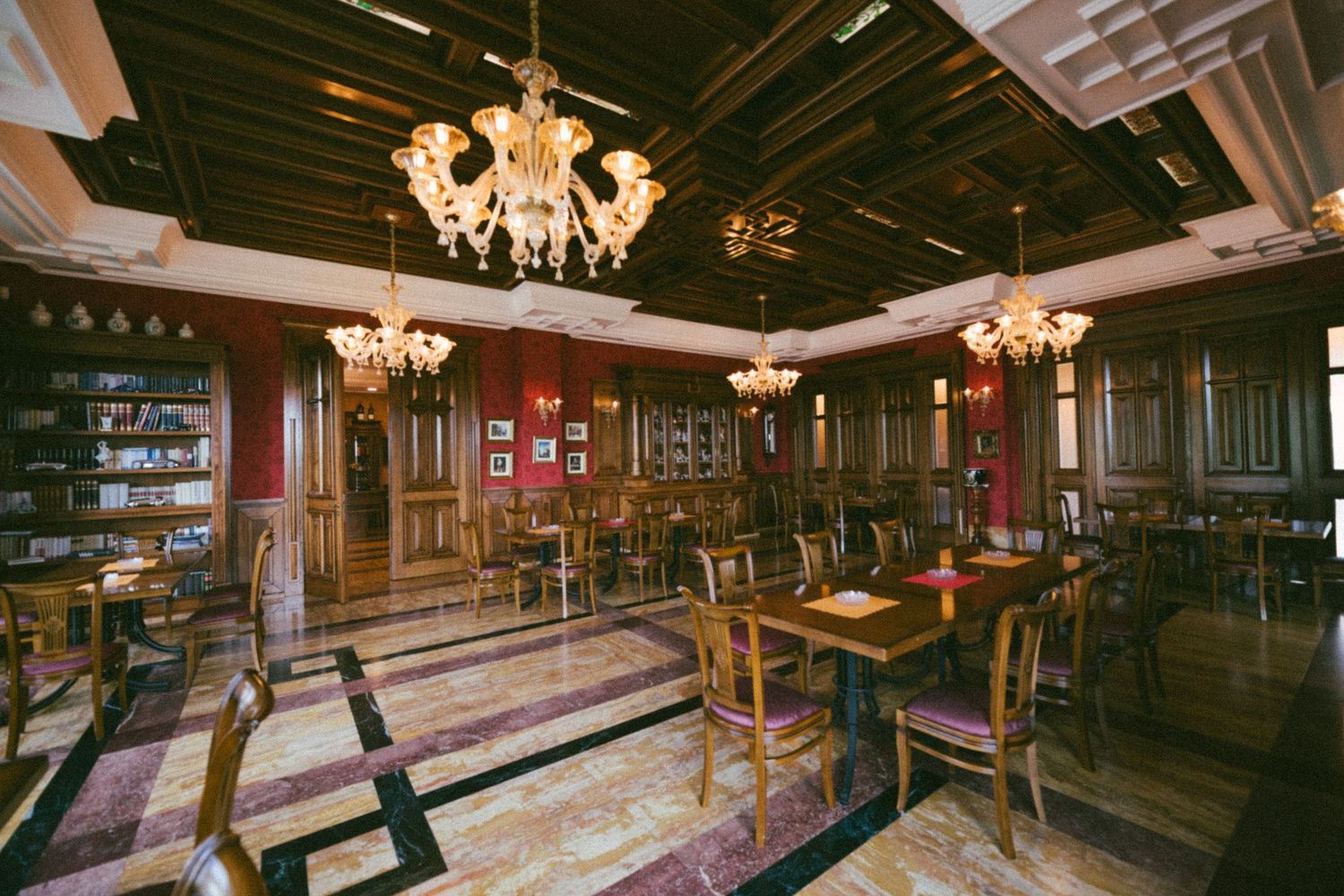 Elegant bar interior with crystal chandeliers, dark wood paneling, and plush seating in a classic vintage style.