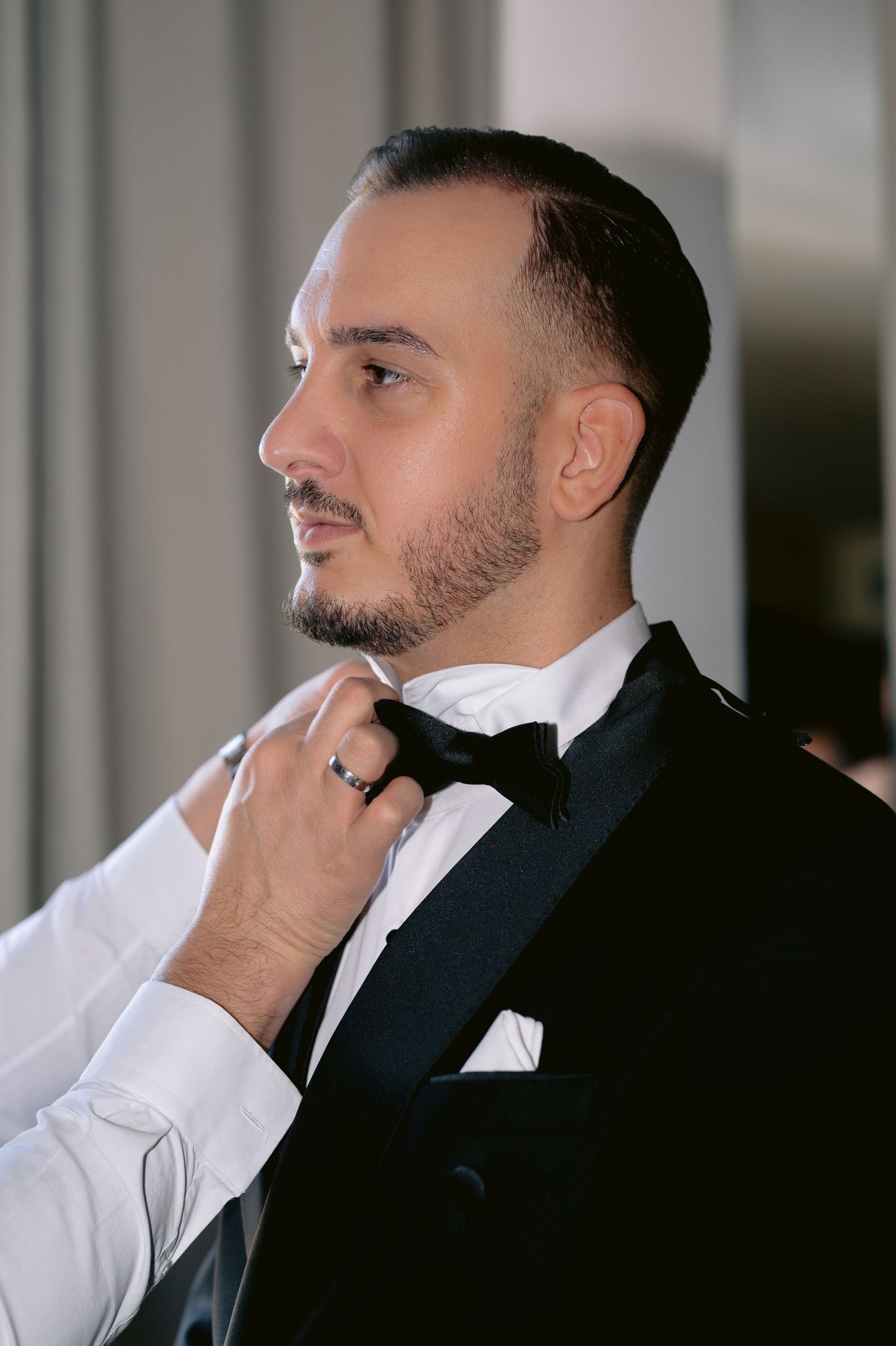 Side profile portrait of person in white dress shirt and black suit jacket looking thoughtfully to the side.