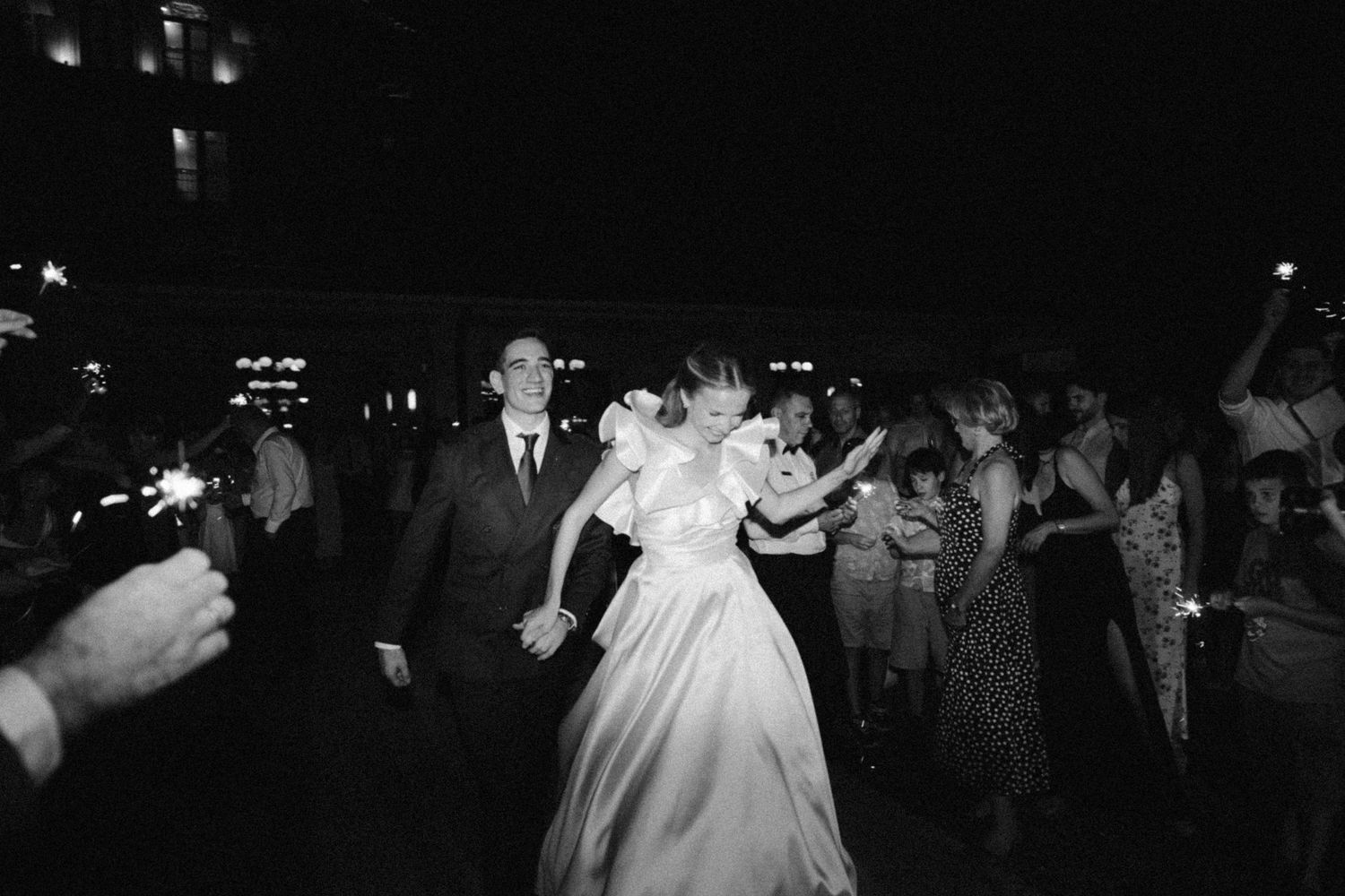 A black and white photograph of a wedding reception dance floor with guests dancing in evening celebration.