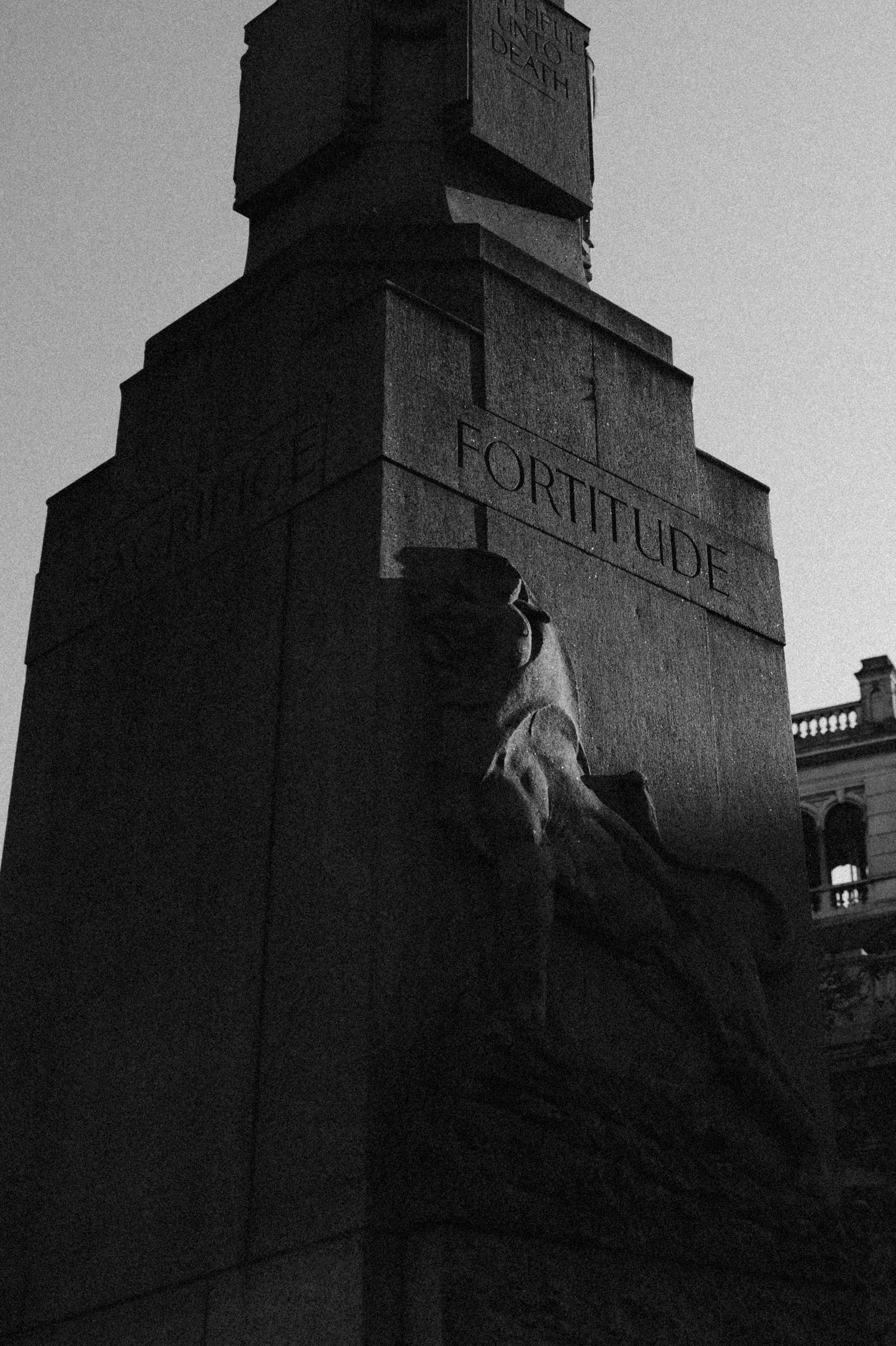 A sequence of dramatic black and white architectural photos showing stone carvings with text on a building facade.