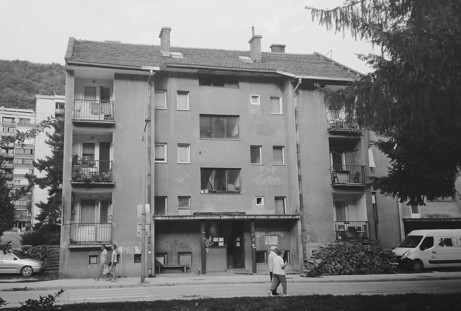 A panoramic view of gray apartment buildings with balconies along a residential street.
