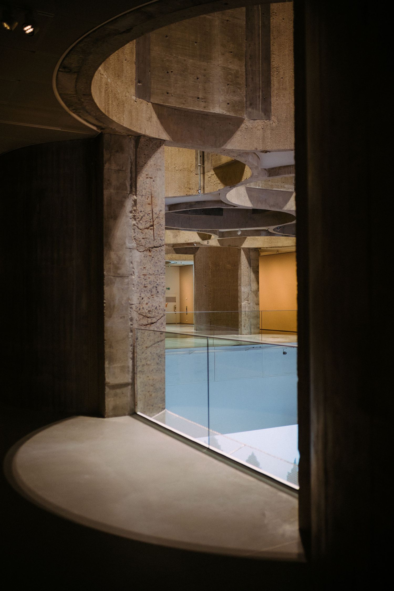 A series of dark architectural interior shots showing curved walls and glass panels in a modern minimalist space.