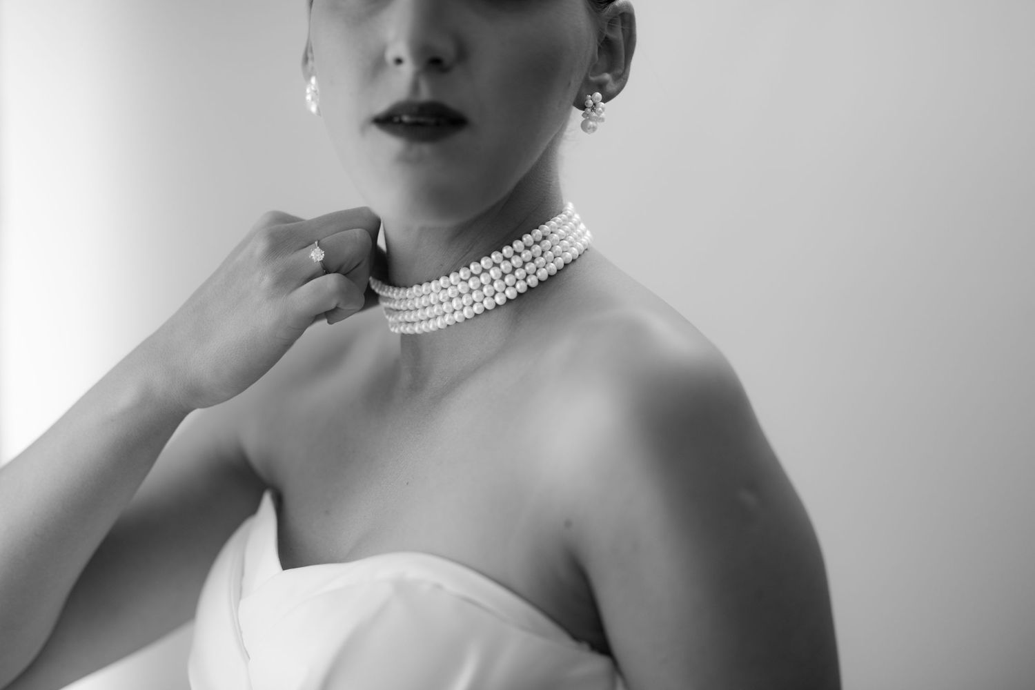 Elegant portrait featuring pearl necklace and classic styling in black and white.