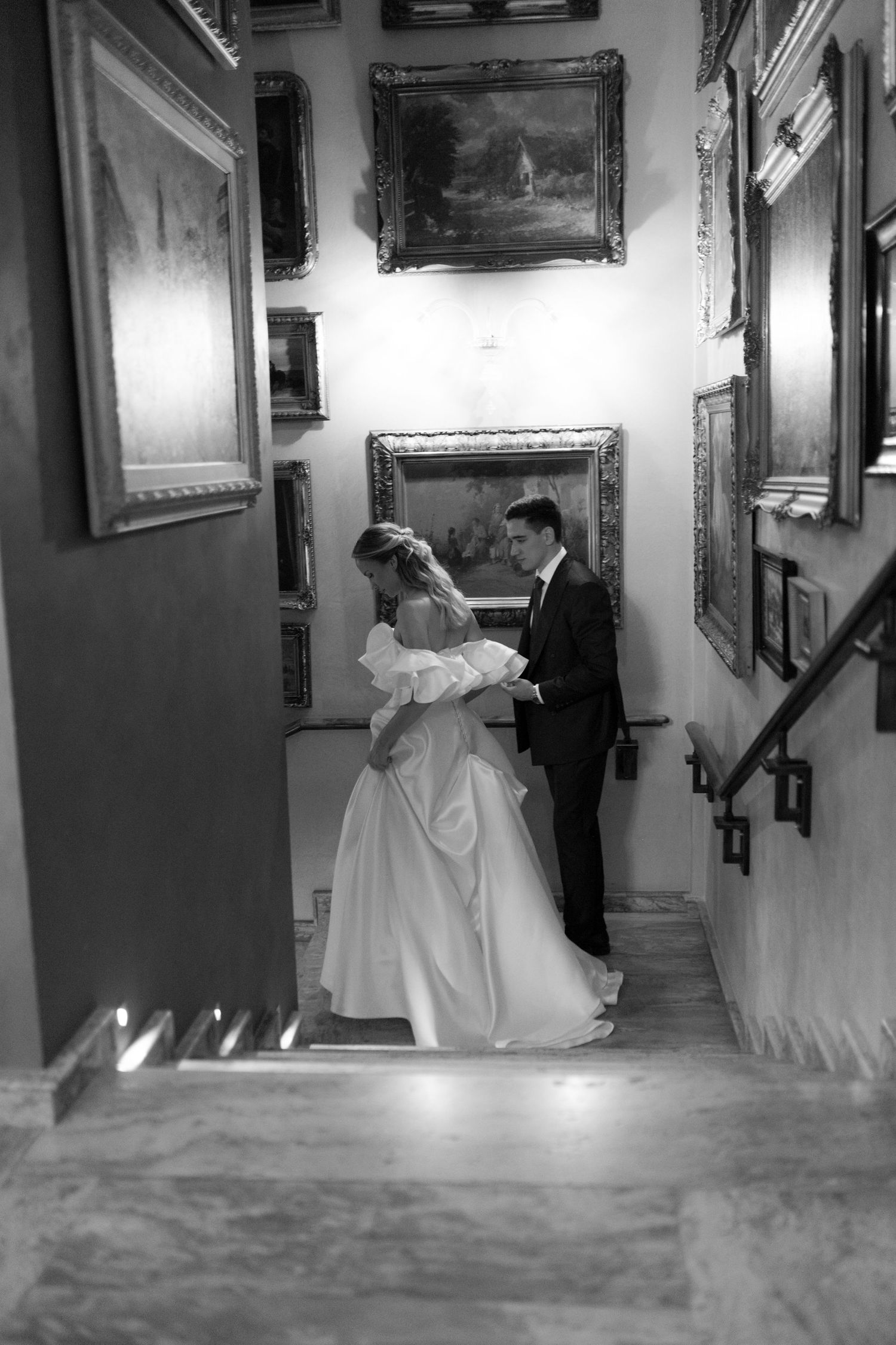 Couple dancing in an elegant hallway decorated with vintage paintings and ornate details.