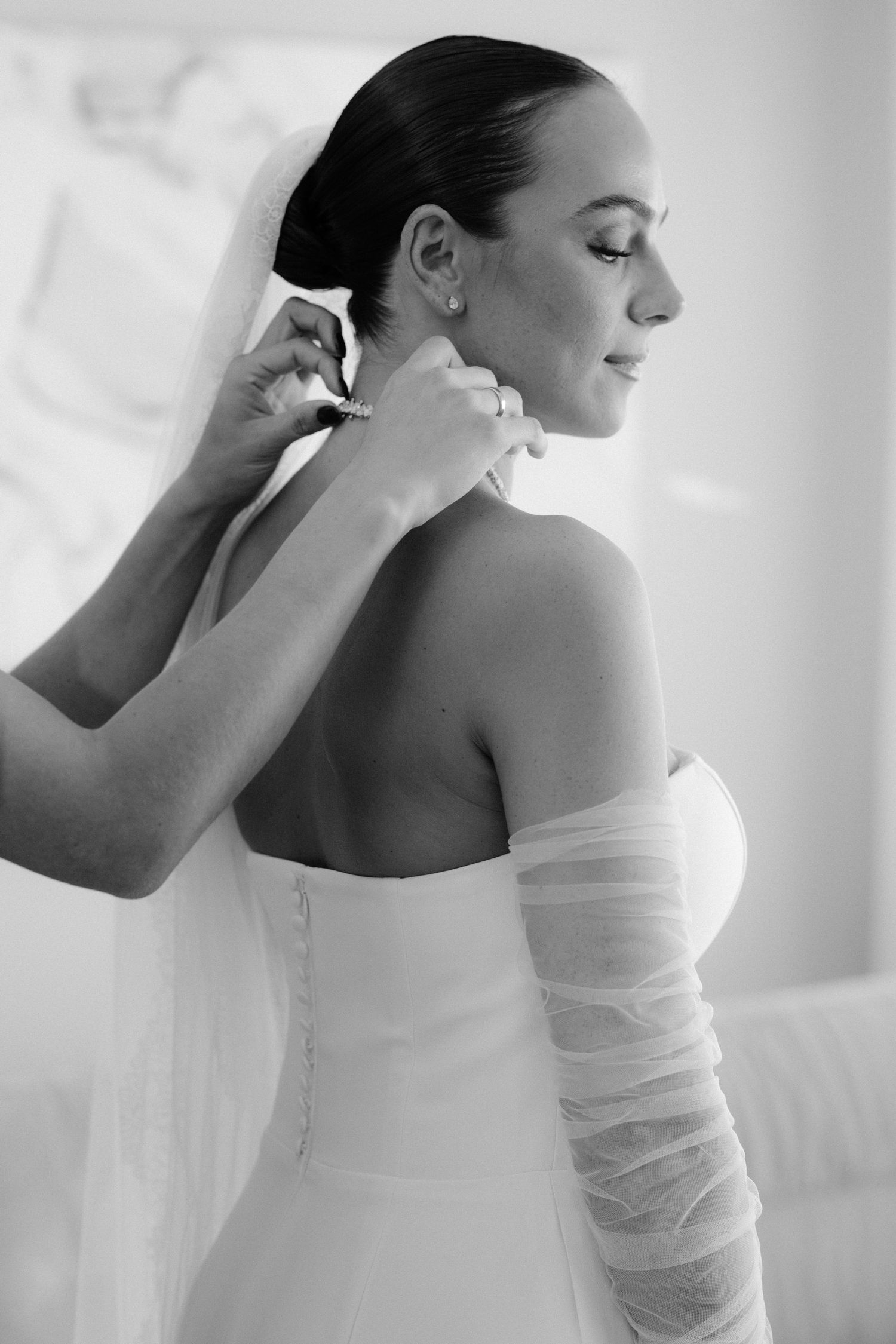 A series of black and white photos showing a bride in an off-shoulder gown adjusting her earrings in soft natural light.