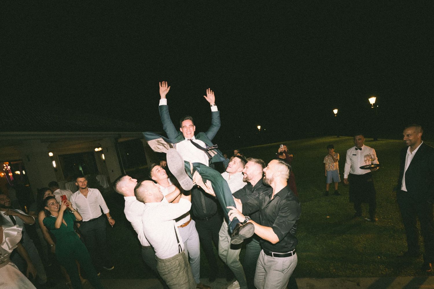 People dancing and celebrating at an outdoor nighttime gathering with a festive atmosphere.