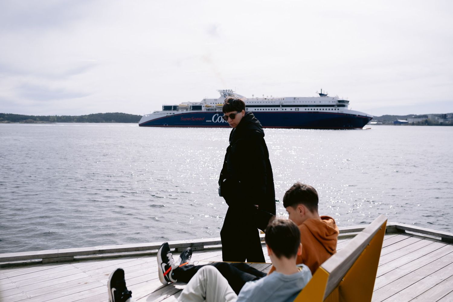 People enjoy a scenic boat ride on calm waters surrounded by natural landscape views on an overcast day.
