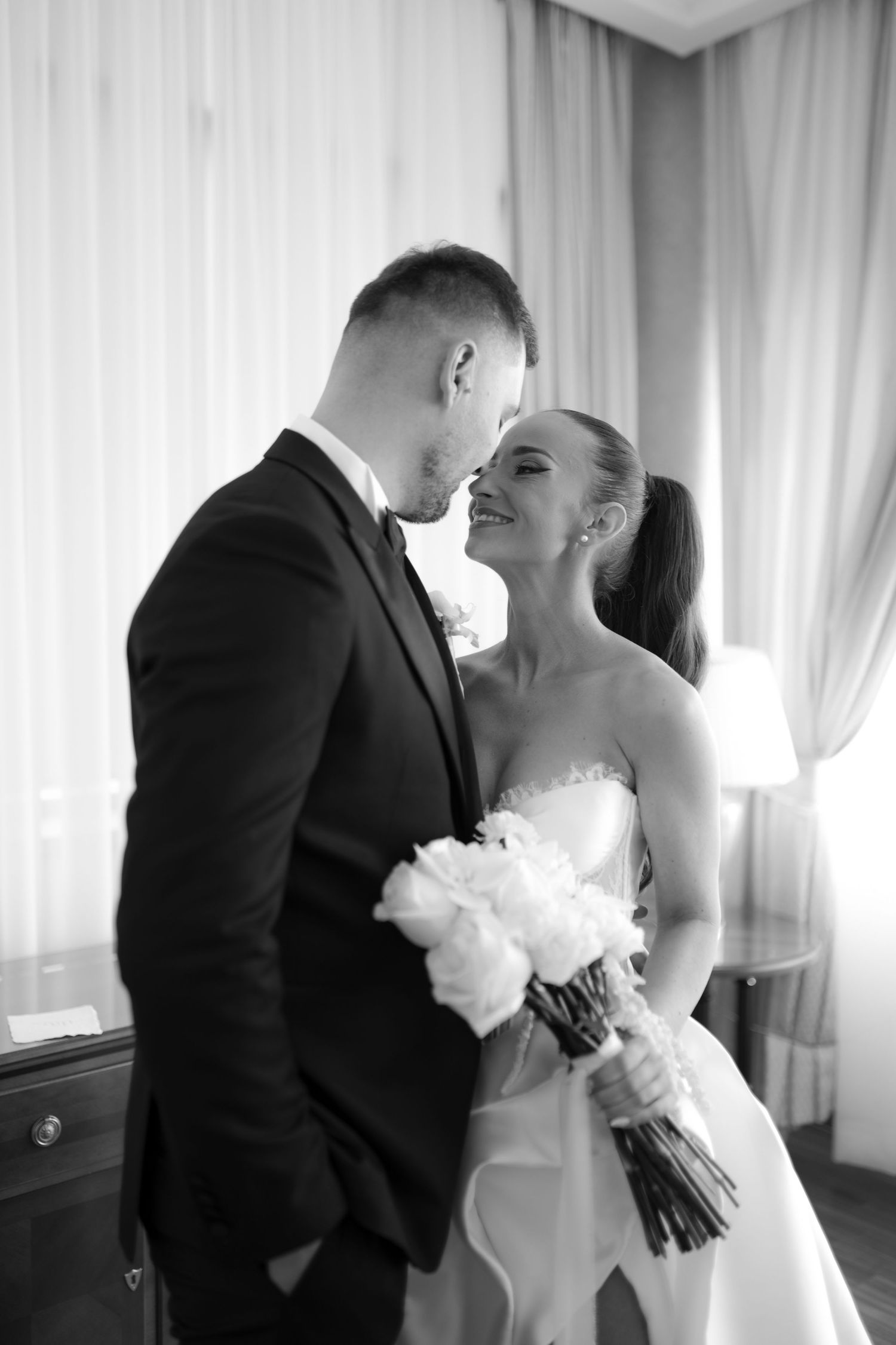 A bride and groom share an intimate black and white moment together during their wedding ceremony.