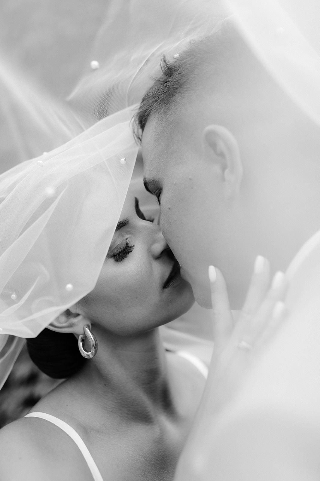 Intimate black and white wedding portrait with delicate veil details.