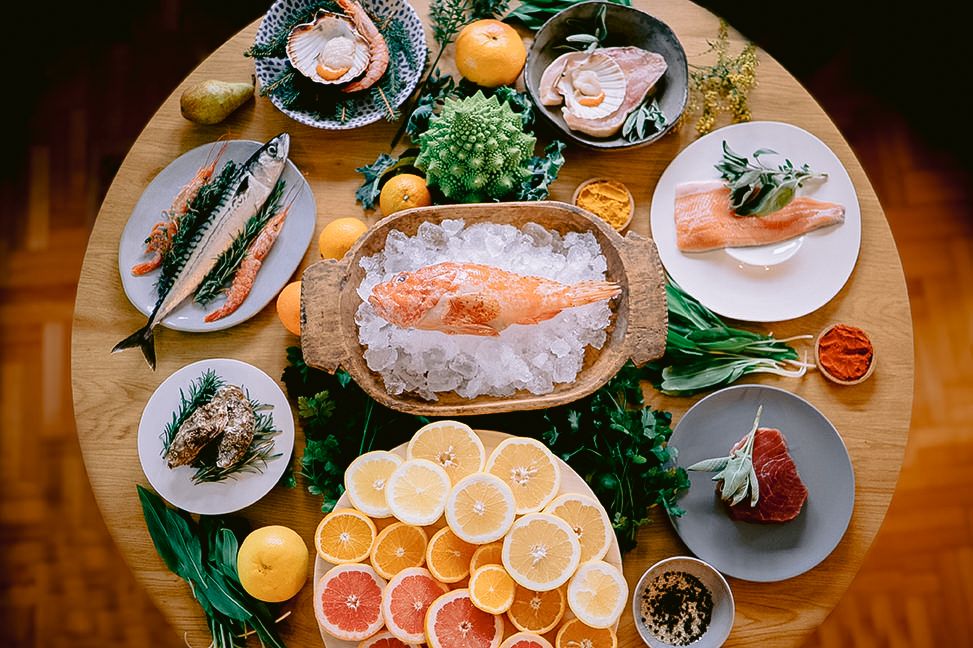 Fresh seafood platter with oysters, shrimp, and citrus garnishes served on decorative plates.