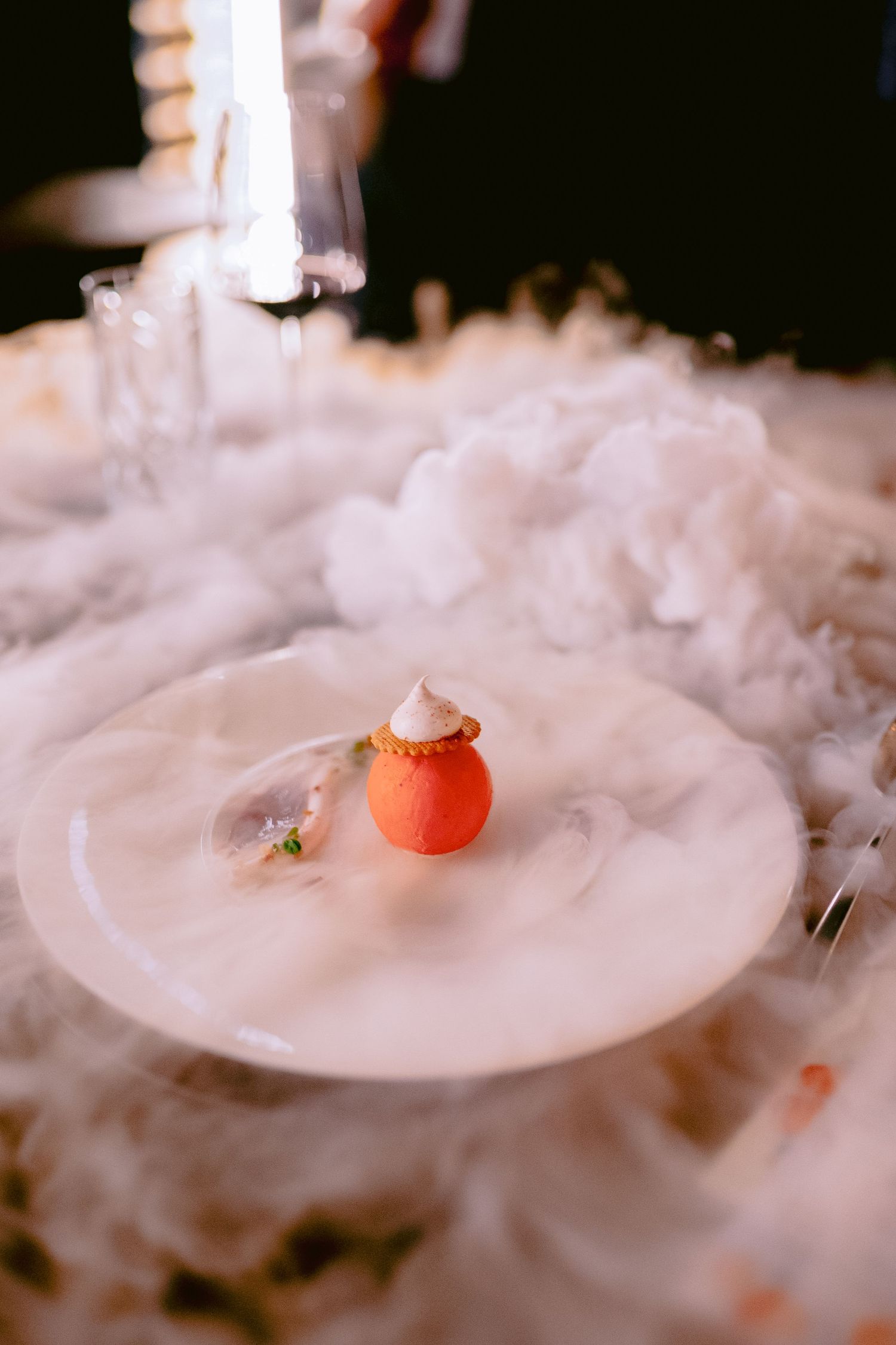 Dramatic presentation of a dish surrounded by theatrical smoke or dry ice effect.