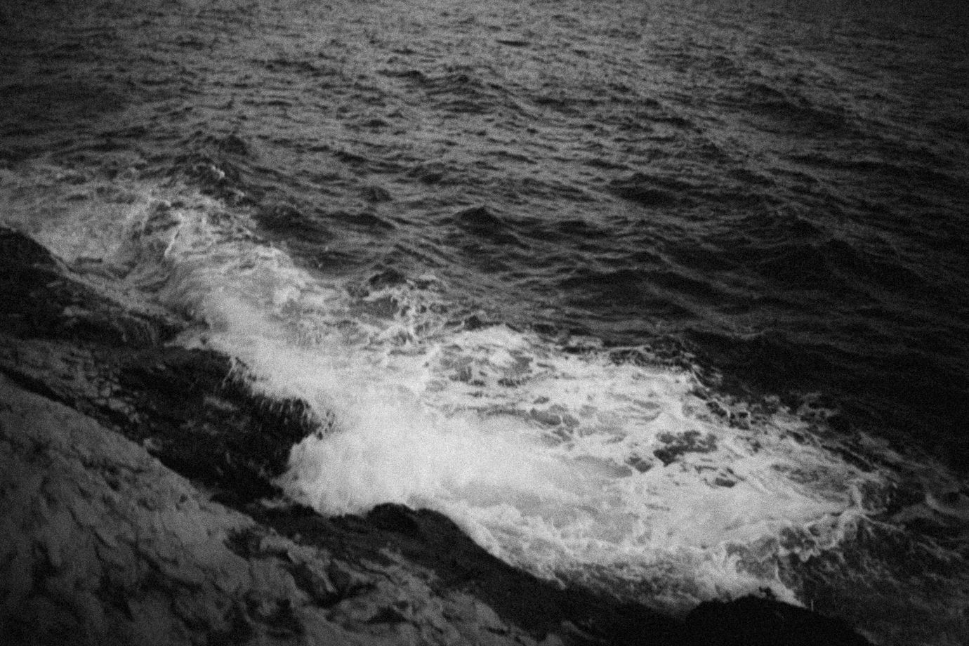 Black and white ocean waves crashing against rocky shore, dramatic seascape photography.