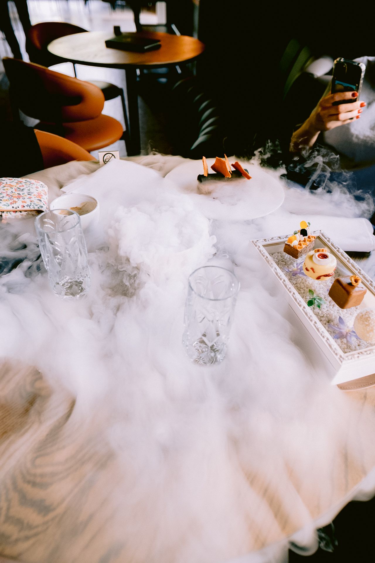 Dramatic presentation of food and drinks on a table with dry ice creating fog effects.