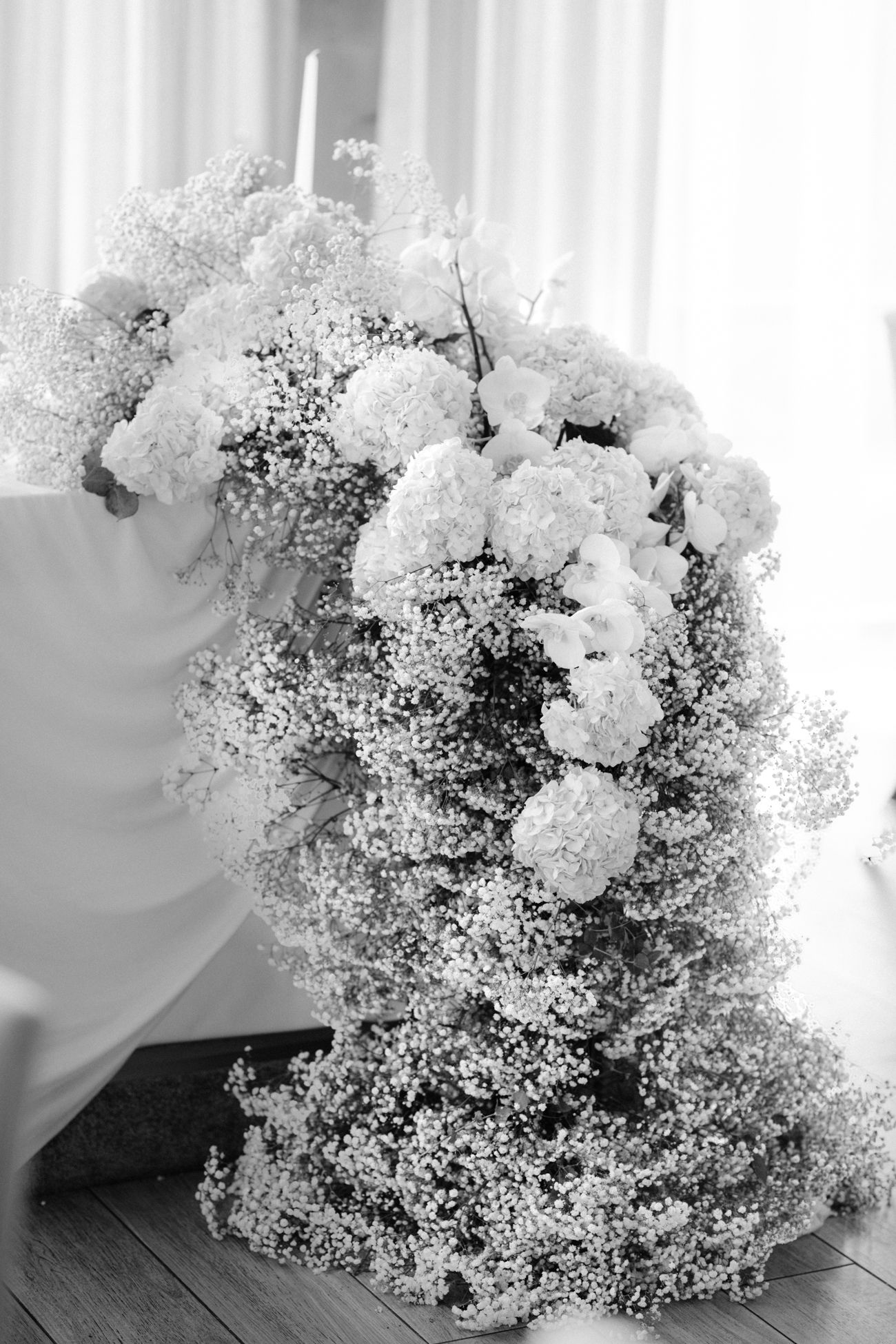 Large dramatic floral arrangement in black and white featuring baby's breath and hydrangeas.