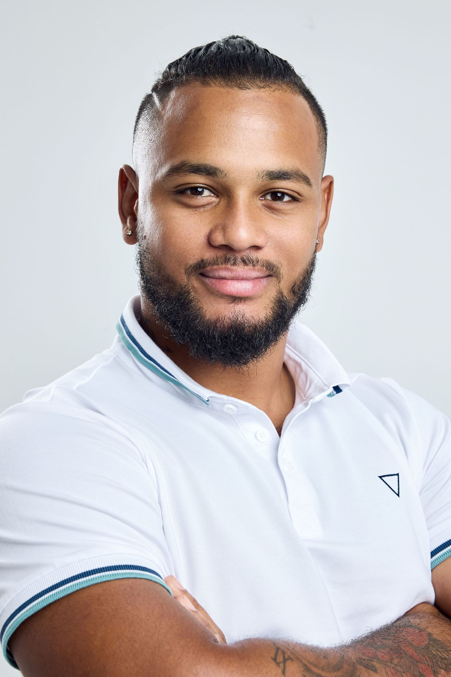 Person in white polo shirt with teal trim smiles warmly in professional portrait series.