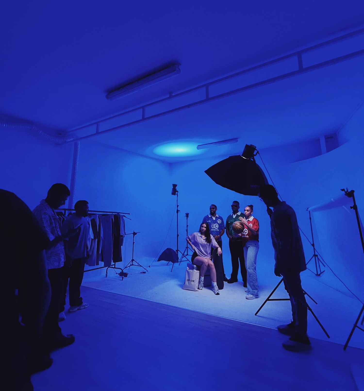 Studio photography session bathed in blue lighting with professional equipment and crew.