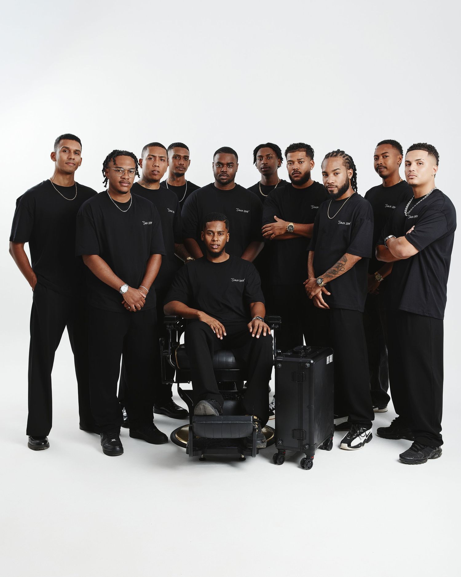 Group photo of people wearing black clothing sitting and standing together against a white background.