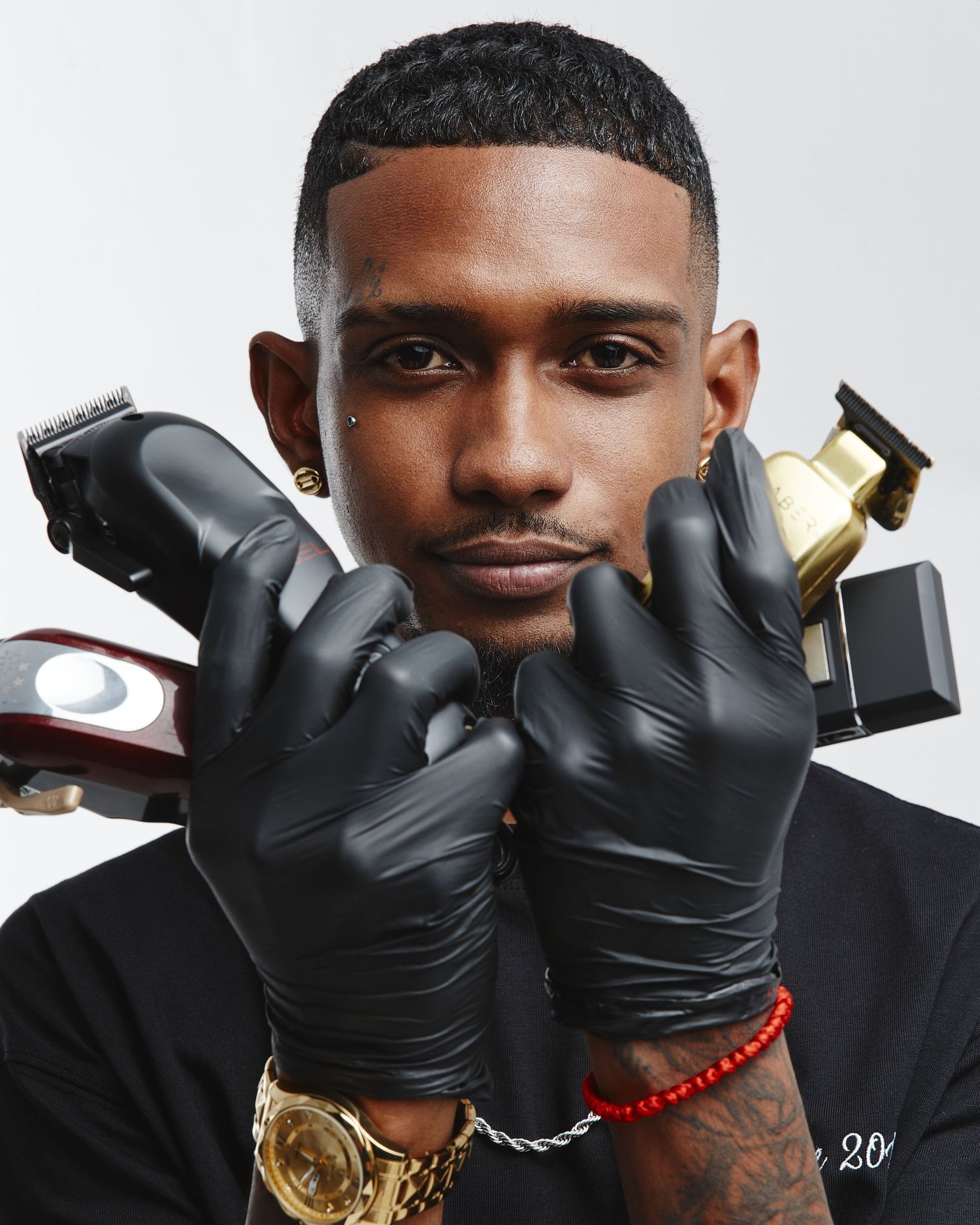 Close-up shots of person wearing black gloves and gold jewelry making hand gestures against white background.