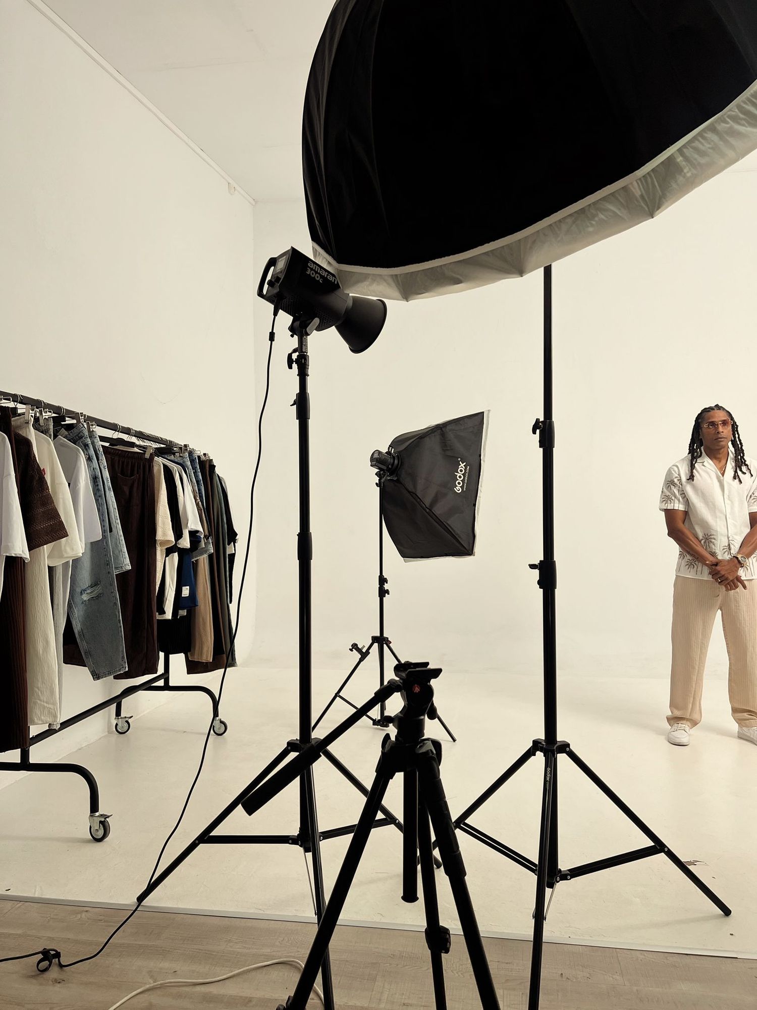 Professional photo studio setup with lighting equipment and clothing rack visible in frame.