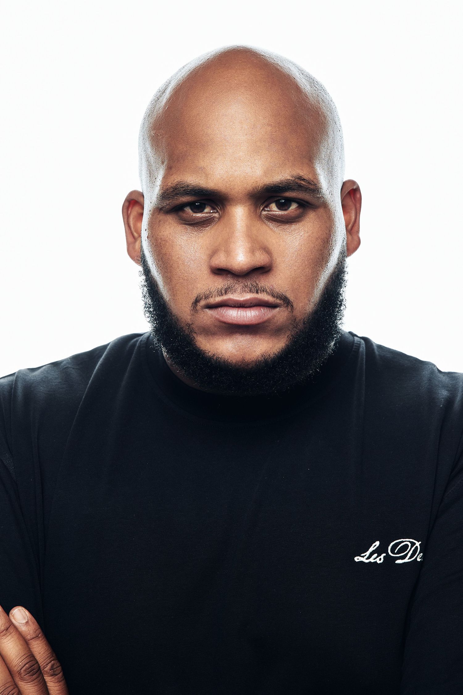 Person in black attire poses against white background for professional headshot series.